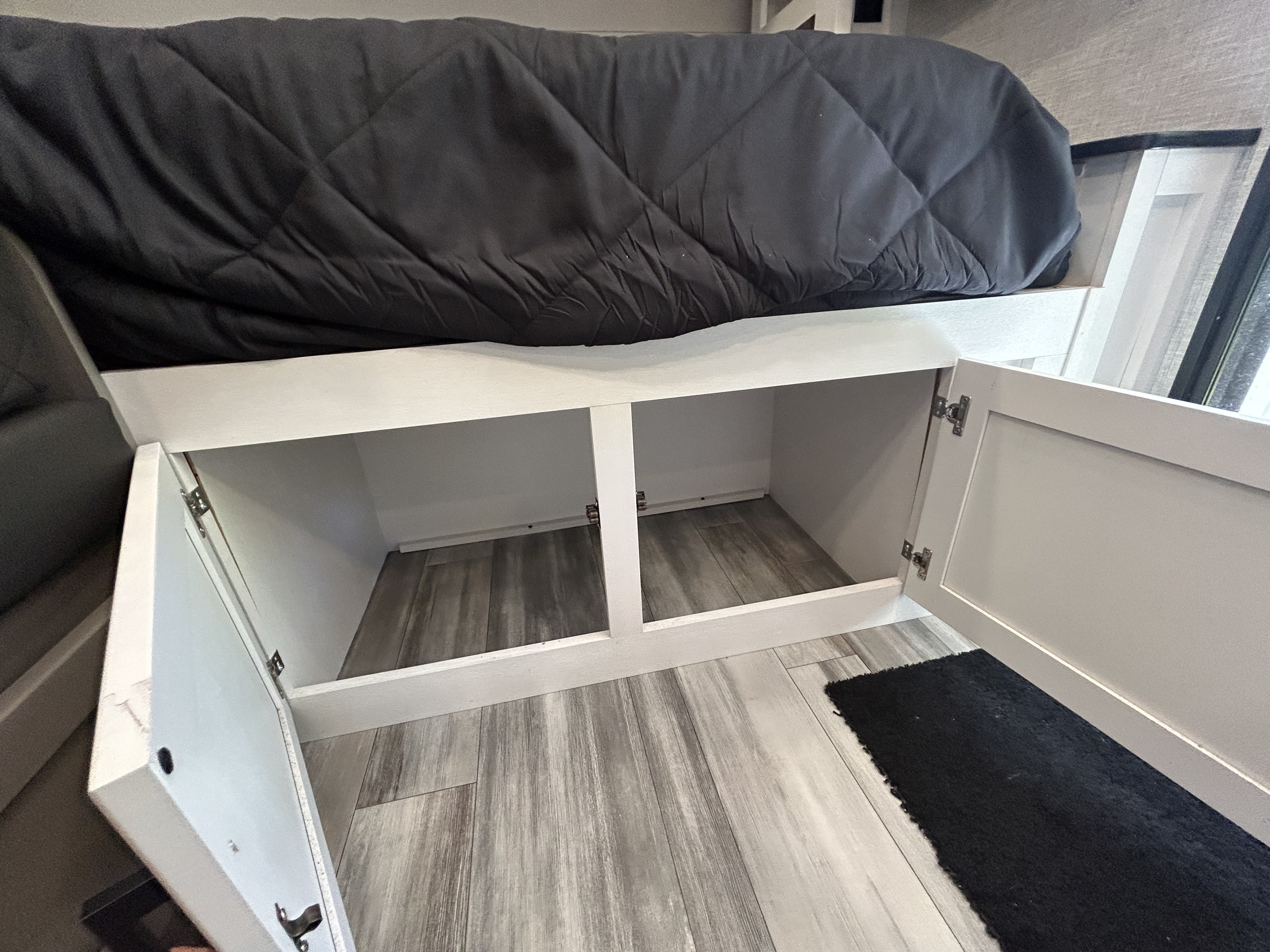 RV rental bedroom: bed platform with under-bed storage (two open), dark comforter on wood-look floor.. Jayco Jay Feather Micro 2023
