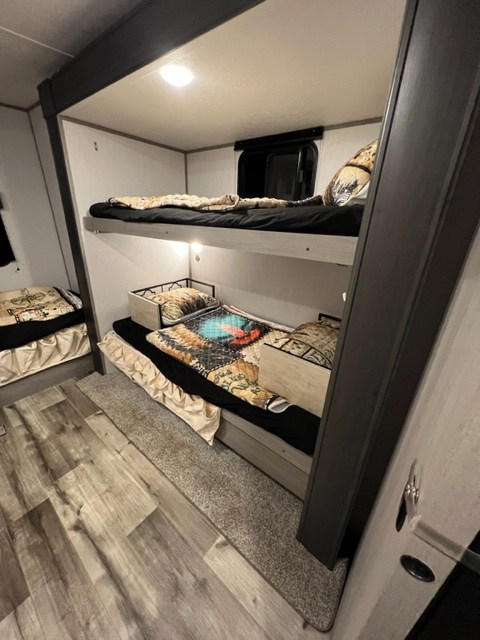 An RV rental's spacious bunkhouse, offering multiple sleeping bunks with cozy bedding and a well-lit interior.. Coachmen 2022 Coleman Dutchmen Coleman Lantern 334BH 2022