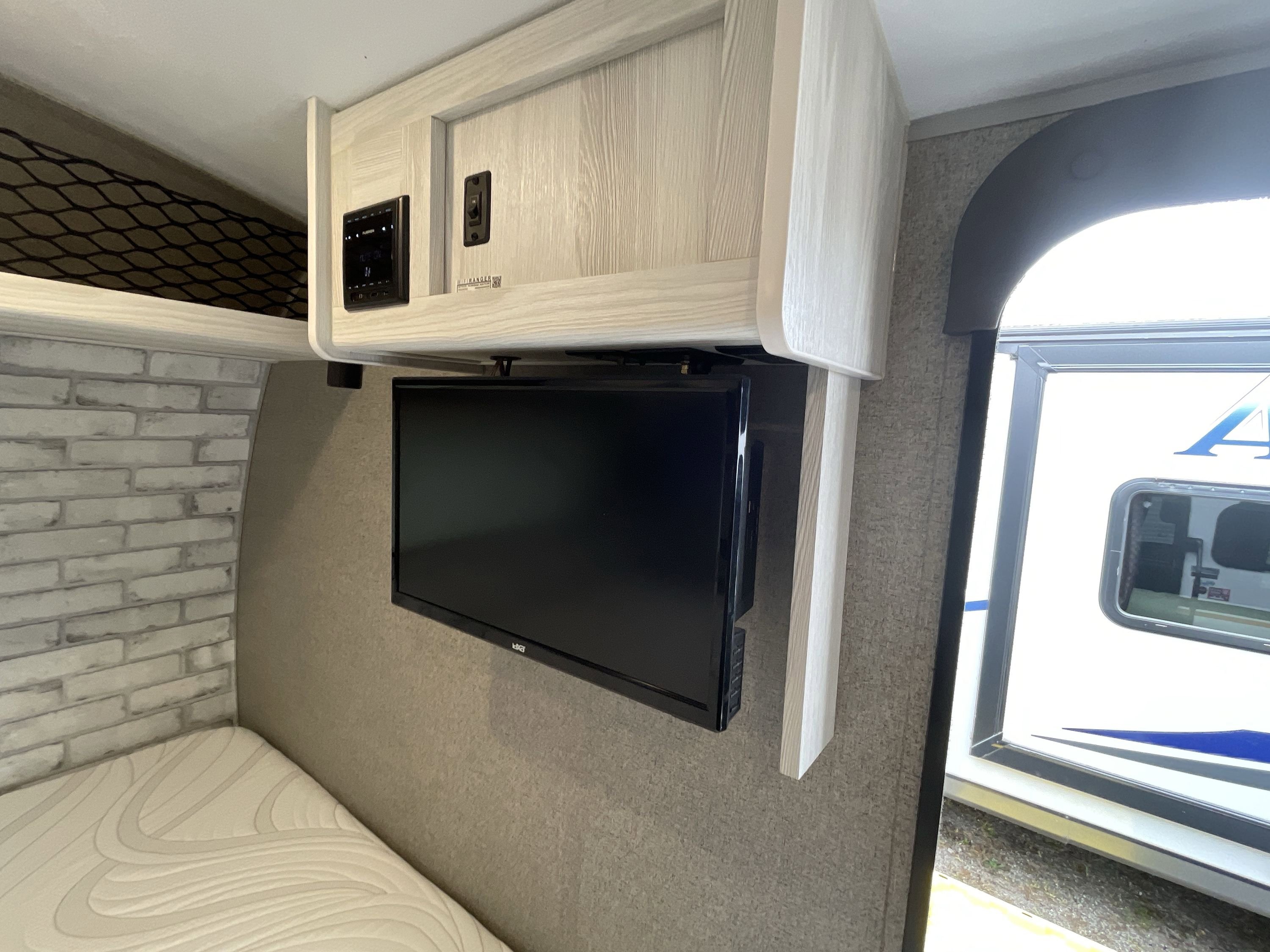 RV rental's inviting bedroom with white brick accent wall, mounted TV, comfy bed, and overhead controls.. Forest River Rockwood Geo Pro 2022