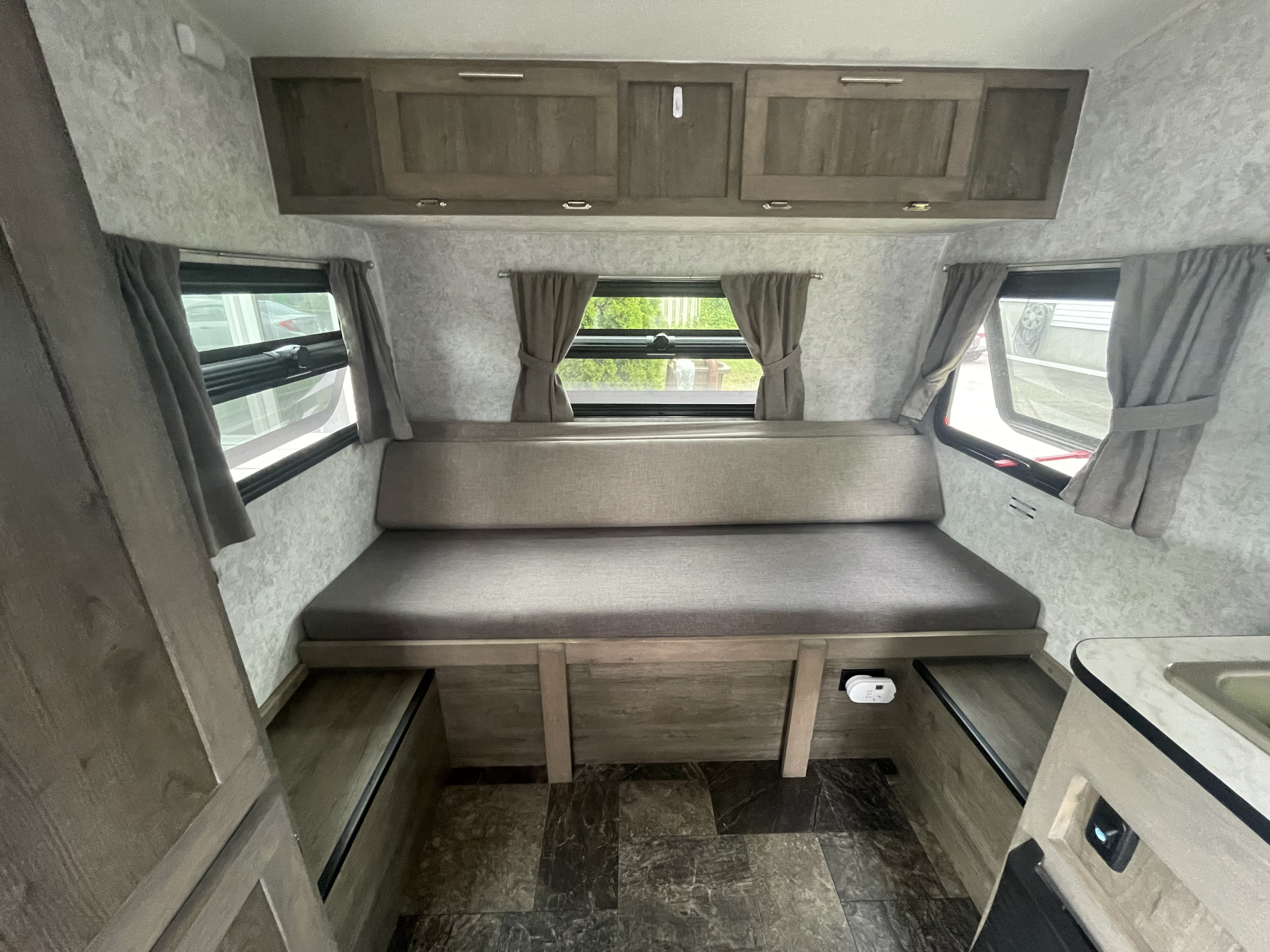 This RV rental's interior boasts a comfortable dinette/bed area, overhead storage, and windows with privacy curtains.. Prolite Prolite Trailer 2022