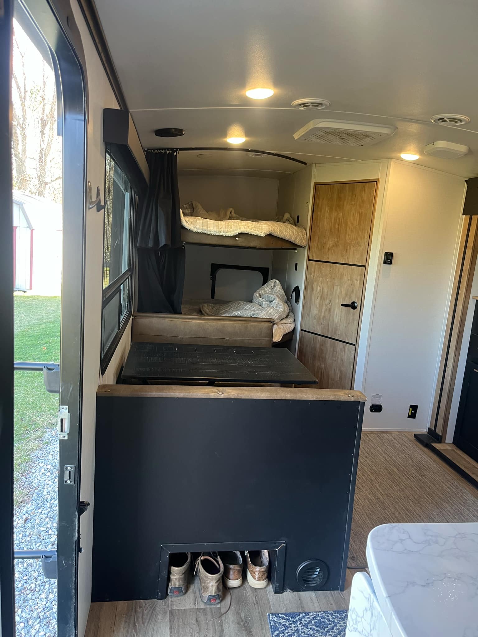 Interior of an RV rental: A well-designed bunkhouse area with beds, a dinette table, and storage solutions for camping trips.. Keystone Outback 2022