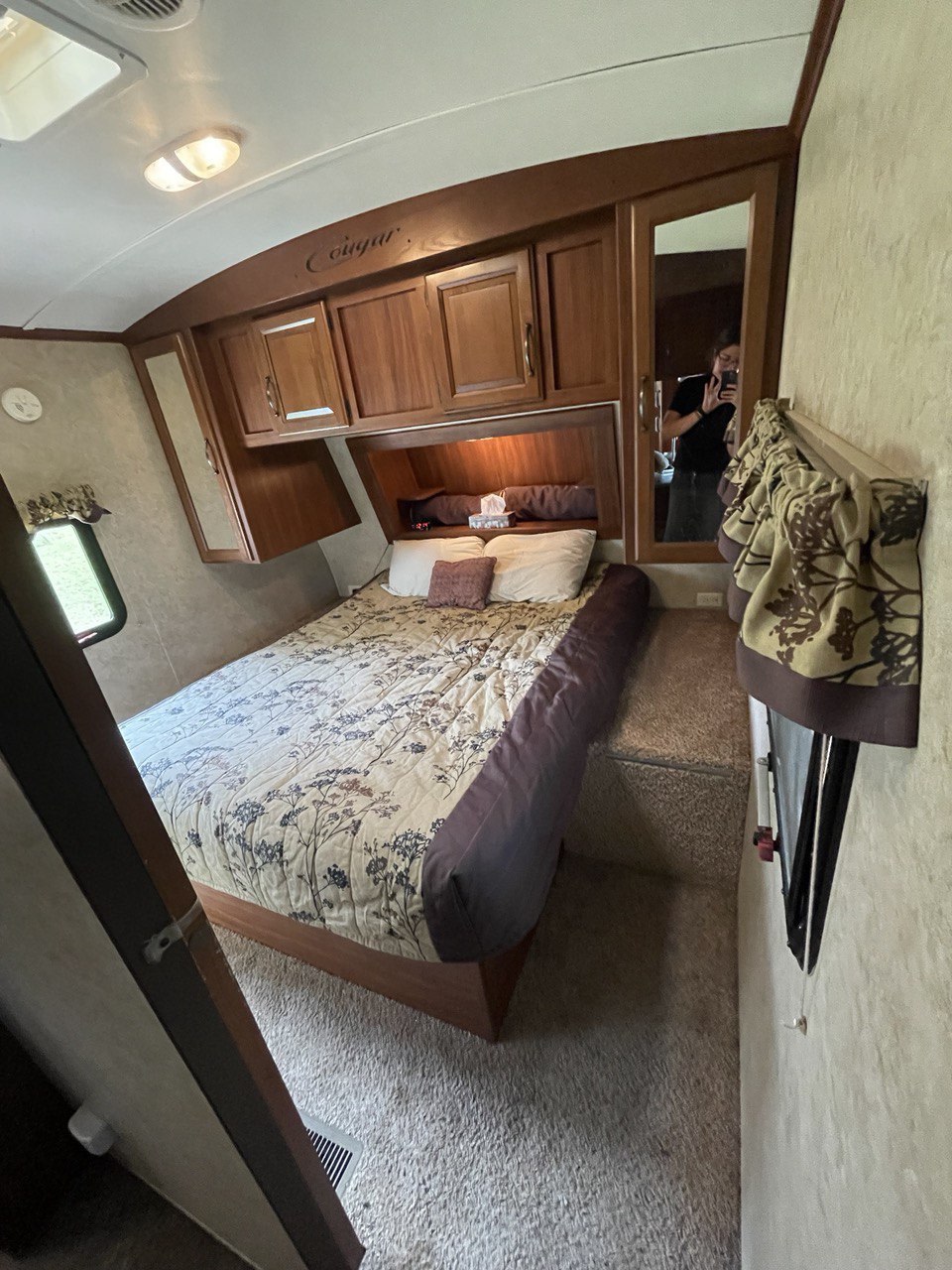 RV rental bedroom with bed, overhead cabinets, and mirrored closet. Ready for your camper travels!. Keystone RV Cougar 2012