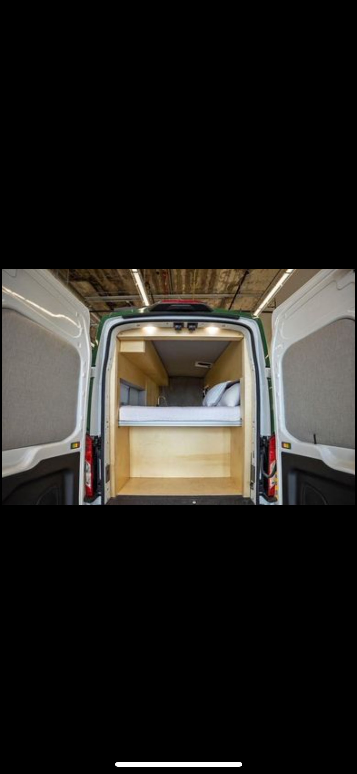 This RV rental shows a cozy camper van interior with a bed and under-bed storage, perfect for your next adventure.. Ford Custom Transit 2022