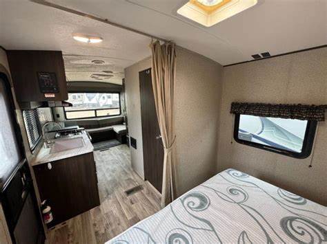 Well-appointed rv rental interior with kitchen, bed, and dining area. Ideal for travel trailer adventures.. Keystone RV Springdale 2019