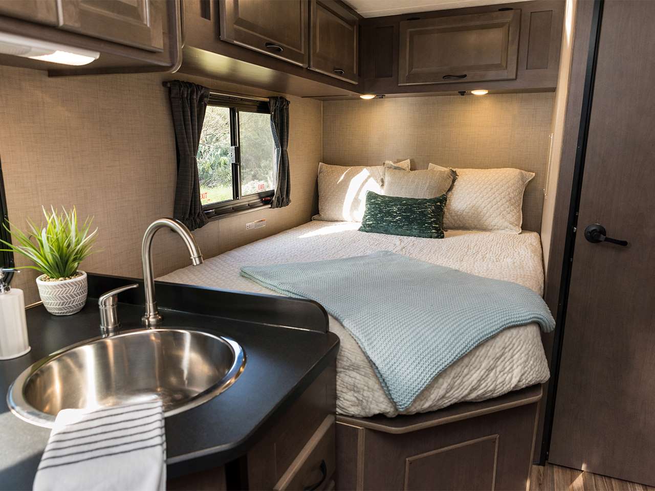 Experience comfortable living in this RV rental's compact bedroom and kitchenette featuring a bed, sink, and storage.. Thor Ford E350 2020