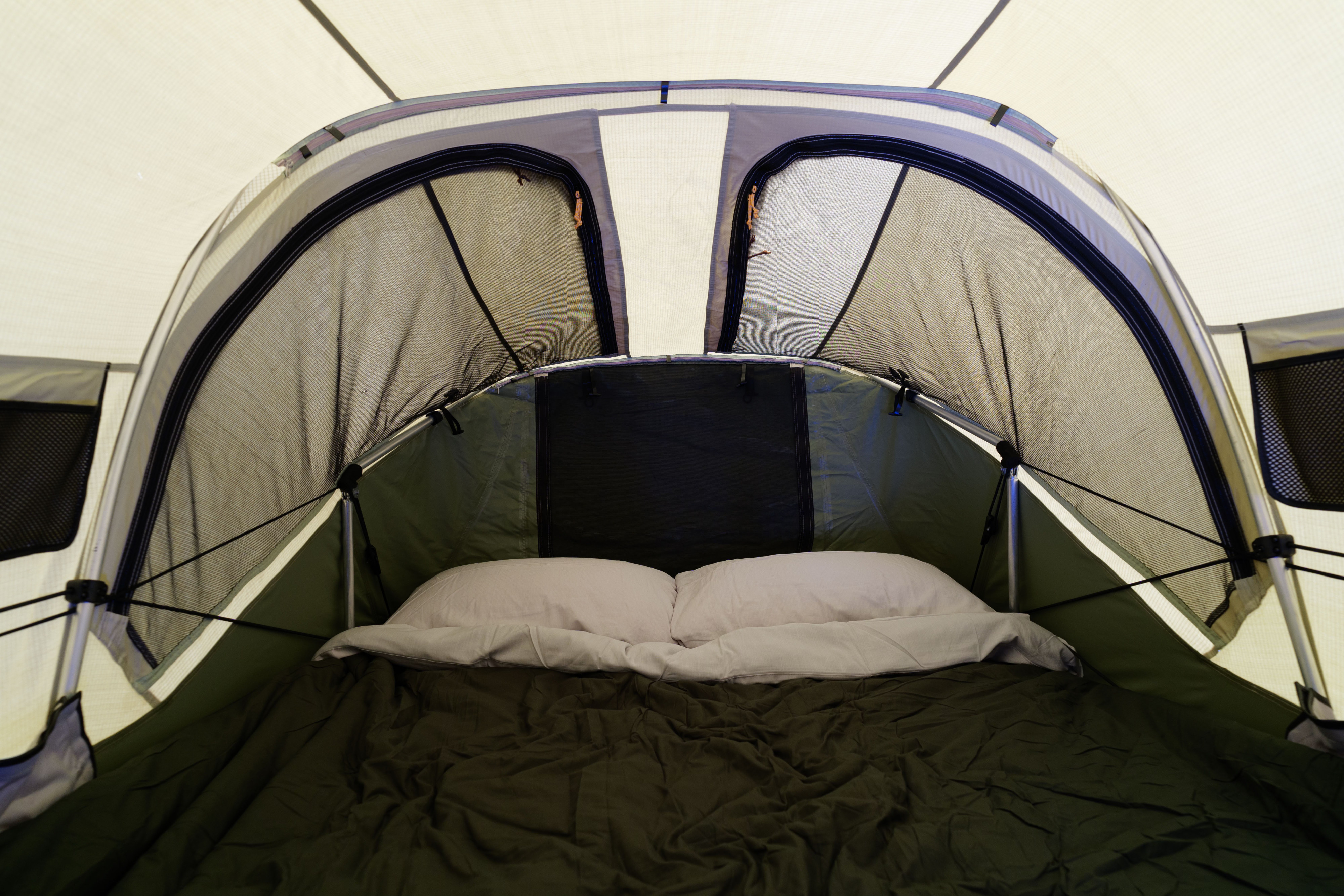 View inside an RV rental's built-in sleeping tent with a comfortable bed, pillows, and mesh openings for ventilation.. Subaru Crosstrek Wilderness 2025