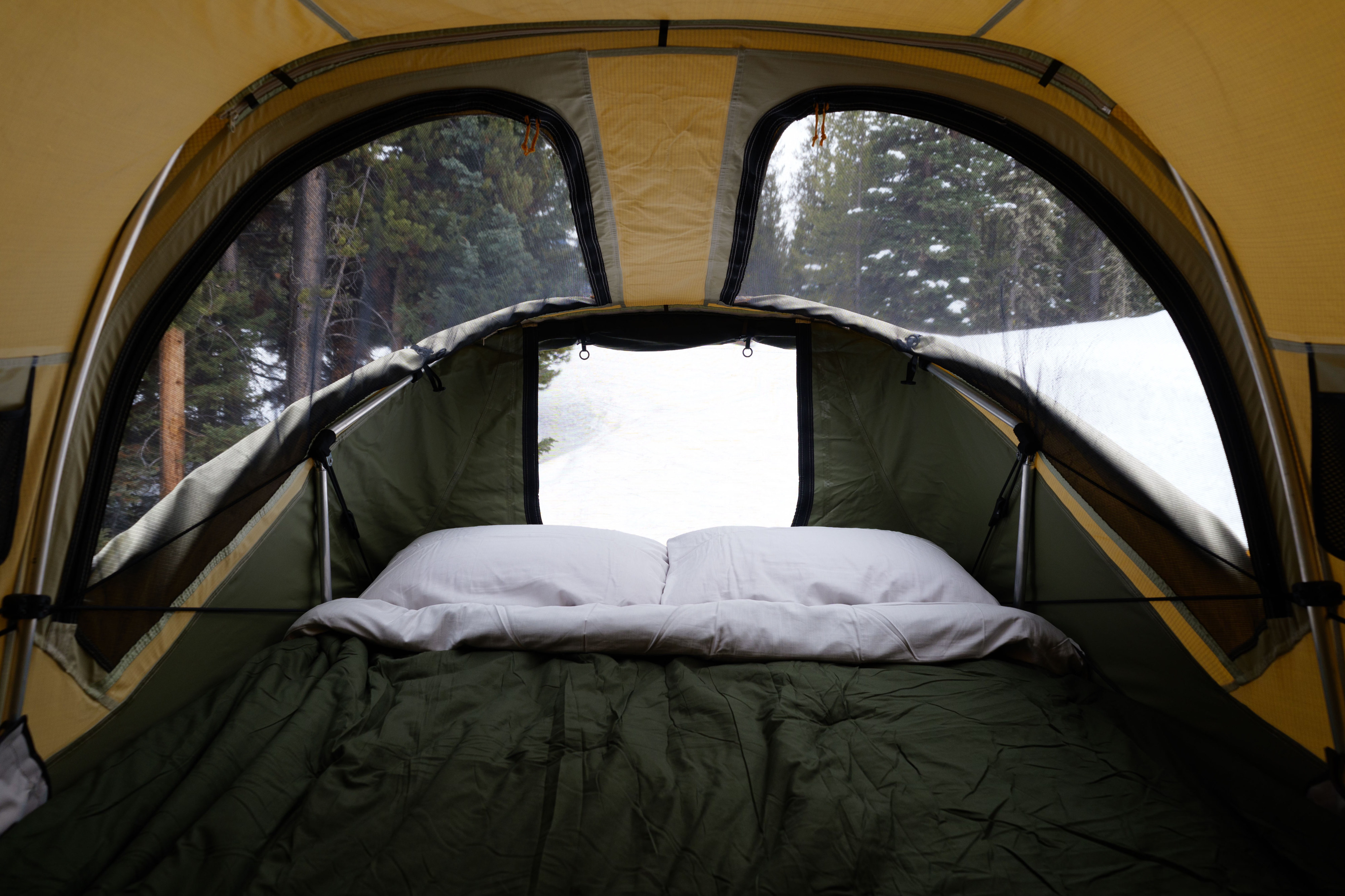 Cozy rooftop tent bedroom in RV rental, with mesh windows offering tranquil snowy forest views.. Subaru Crosstrek Wilderness 2025