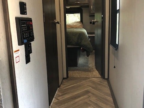 RV rental interior shows a hallway leading to a bedroom. Features a control panel on the left and herringbone flooring.. Astoria 1500 2021