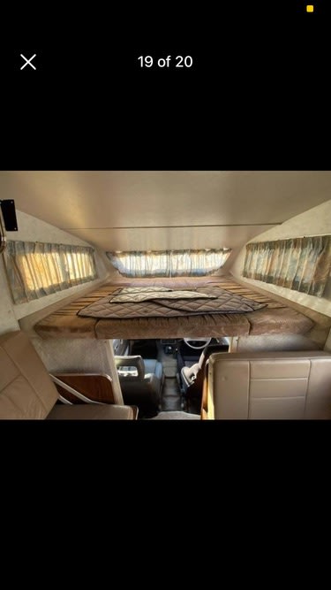 Cozy cab-over bunk and driver's area inside this RV rental. Features a spacious sleeping area with windows.. Isuzu Nqr 450 1993