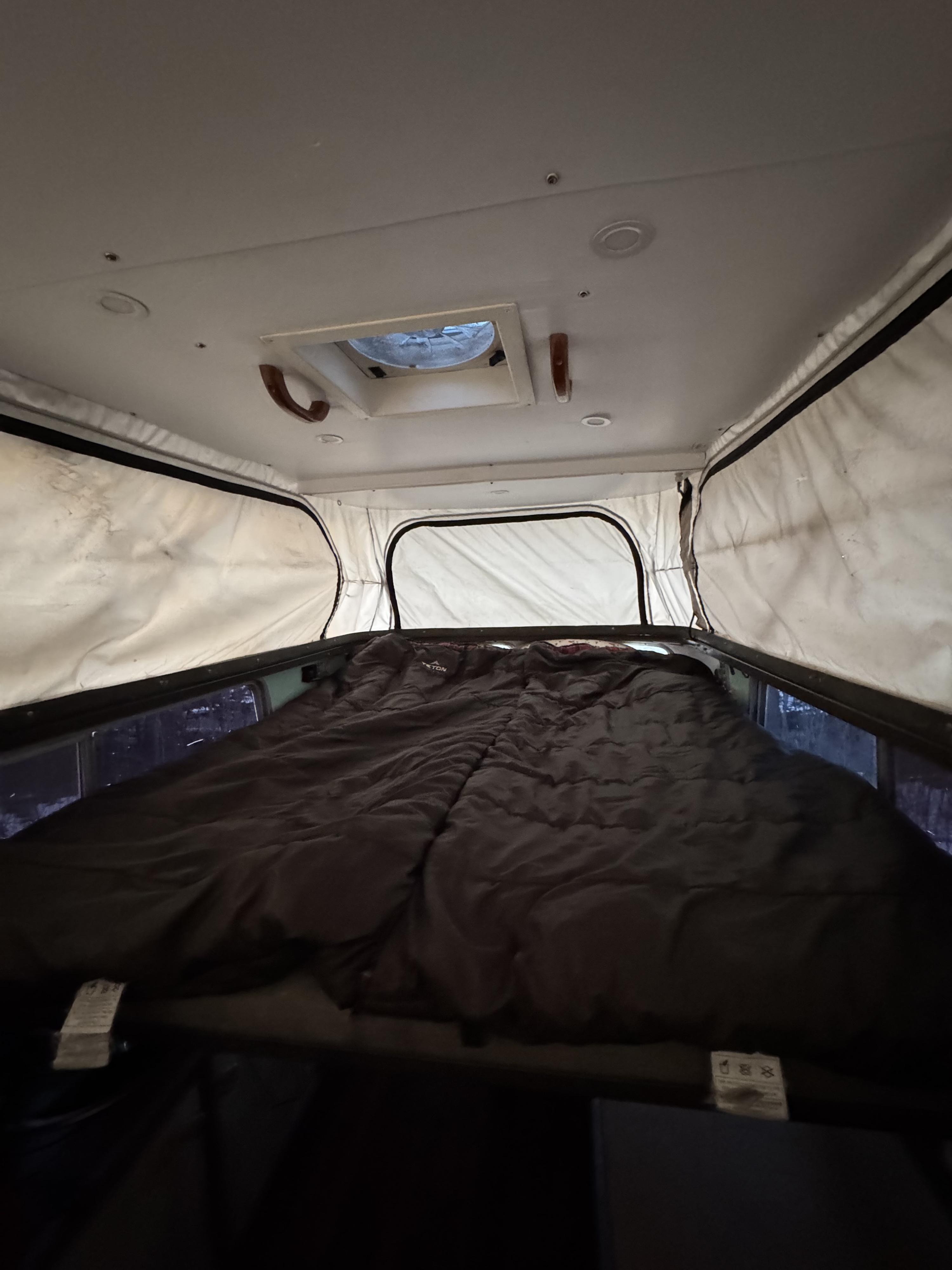 Cozy rv rental pop-top camper interior with bed & roof vent. Perfect for camping adventures.. Toyota Hilux 1982