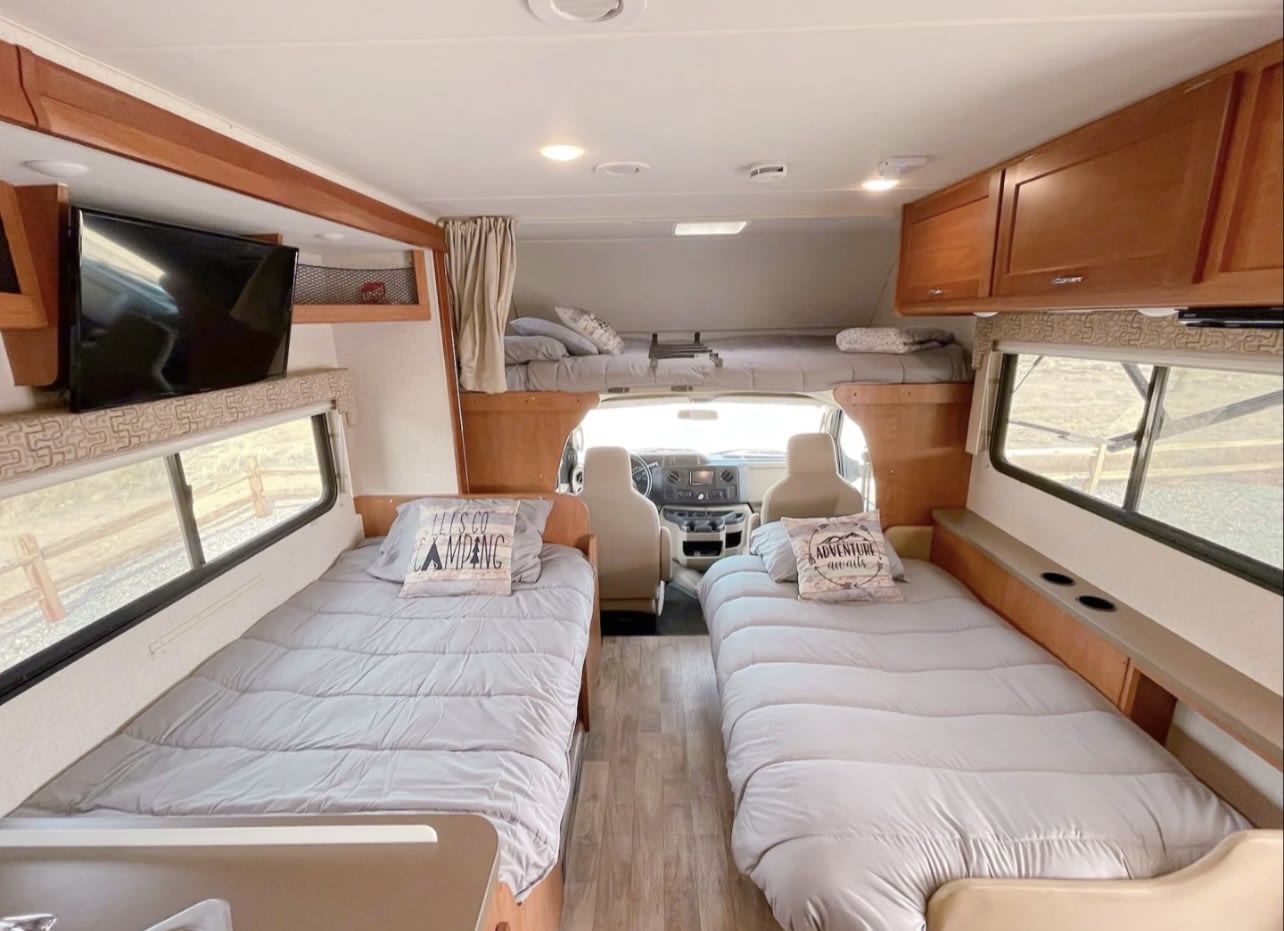 Spacious rv rental interior showing three beds, TV, and front cab area. Ideal for family adventures.. Winnebago Minnie Winnie 2017