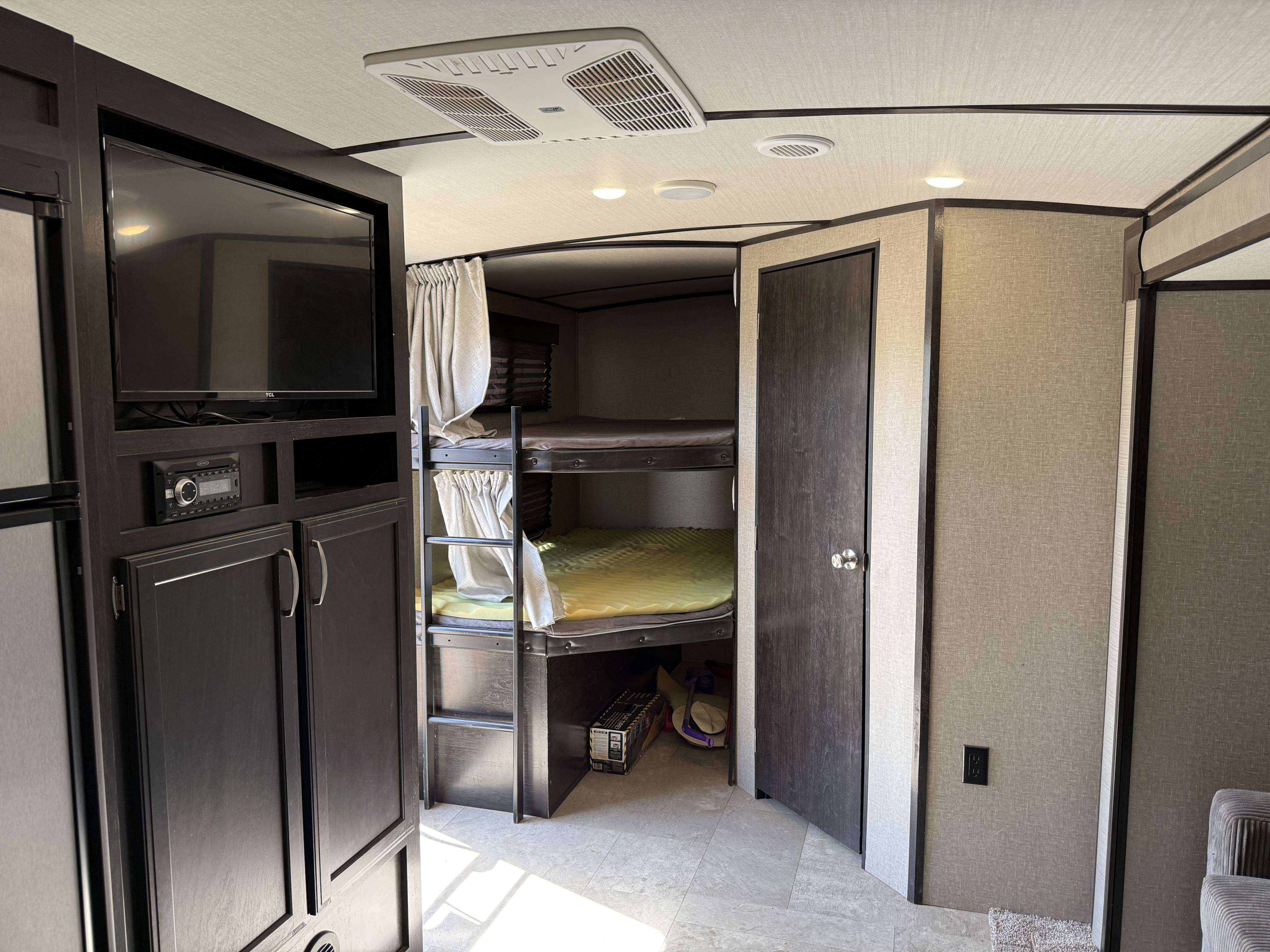 Cozy RV rental interior with bunk beds, TV, and audio system, perfect for family adventures.. Grand Design De Imagine 2019