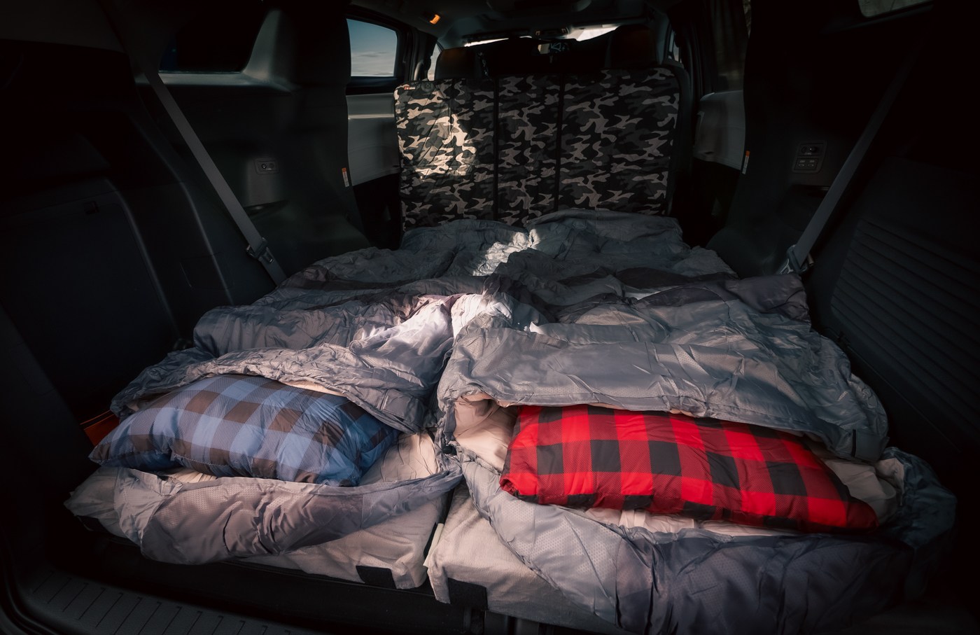 Cozy SUV car camping setup with two sleeping bags & plaid pillows, ideal for an RV rental alternative on your road trip.. Toyota Other 2025