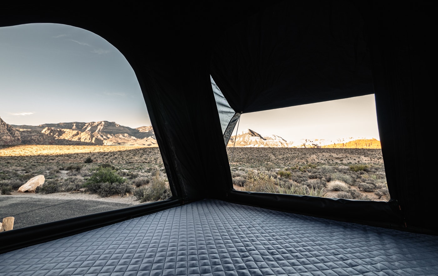 Comfortable RV rental view: quilted bed inside tent with scenic desert mountains at sunrise.. Toyota Other 2025