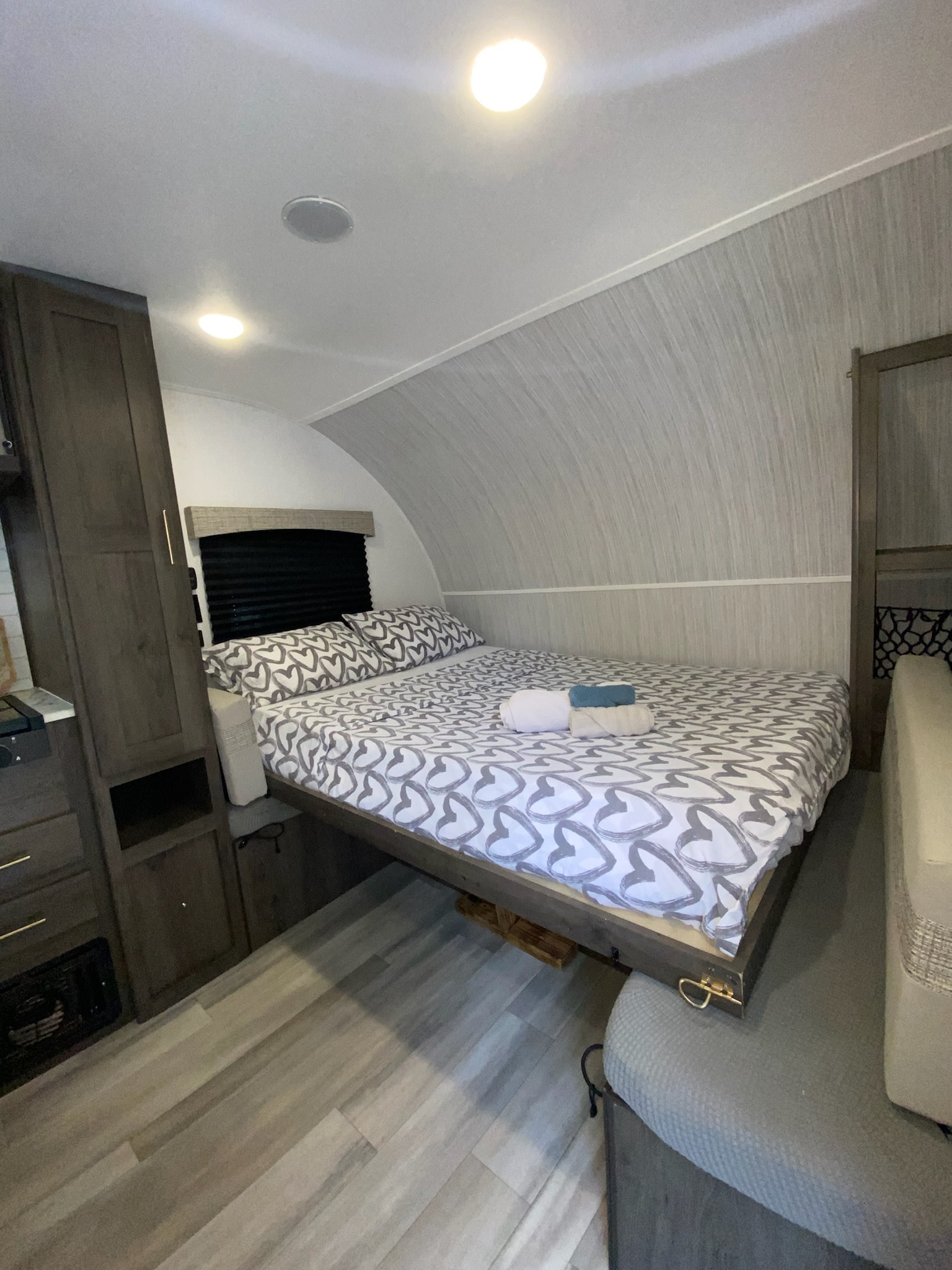 Cozy RV rental bedroom with a heart-patterned bed, modern cabinetry, and curved walls. Perfect for travel comfort.. Forest River Viking TD 2023