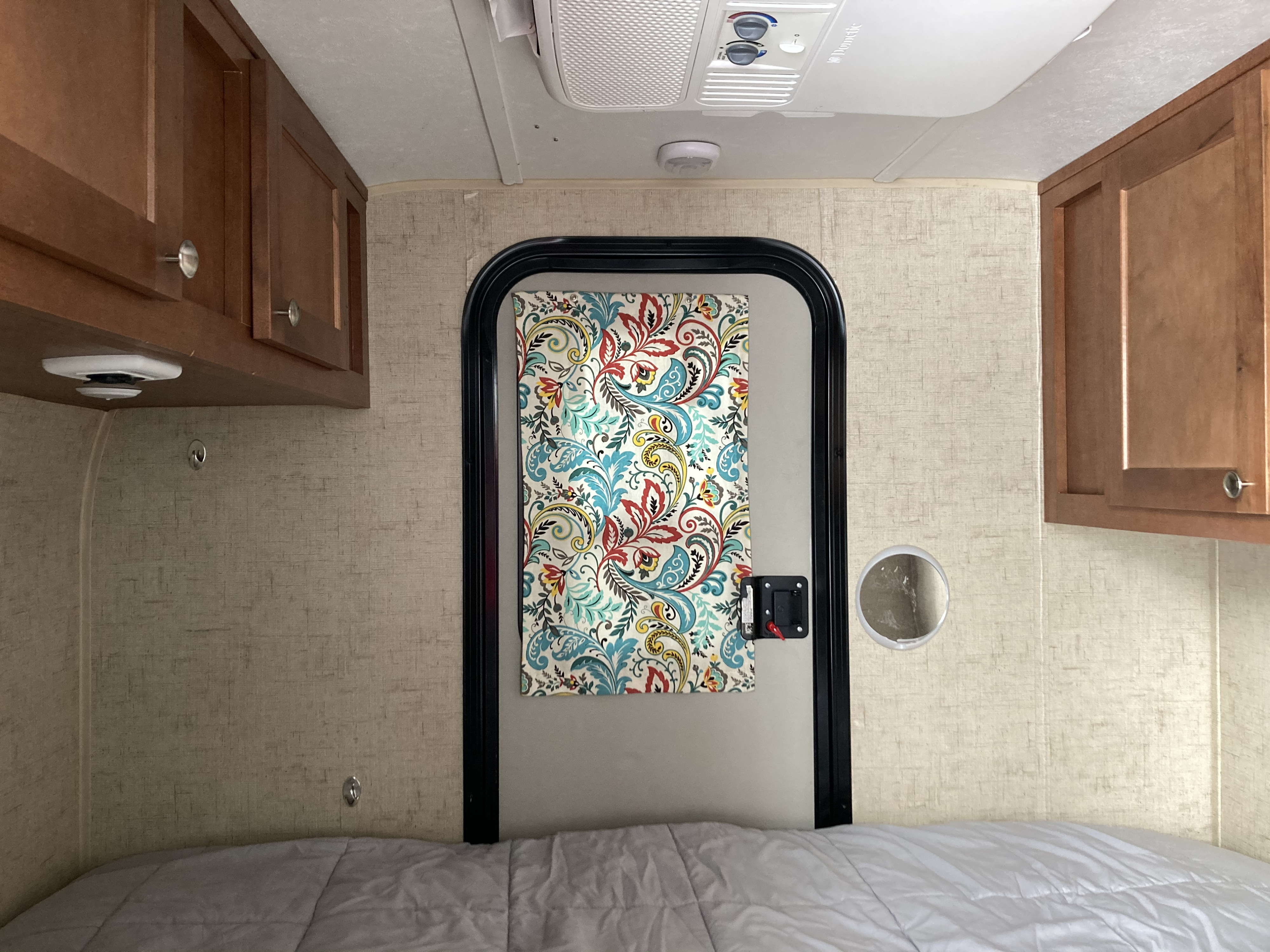 RV rental interior: cozy sleeping area with bed, wood cabinets, and AC.. Riverside RV Retro 2017