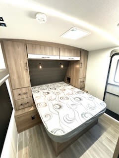 This RV rental bedroom offers a comfortable bed, ample overhead storage, and built-in cabinets for your travels.. Grand Design Imagine 2024