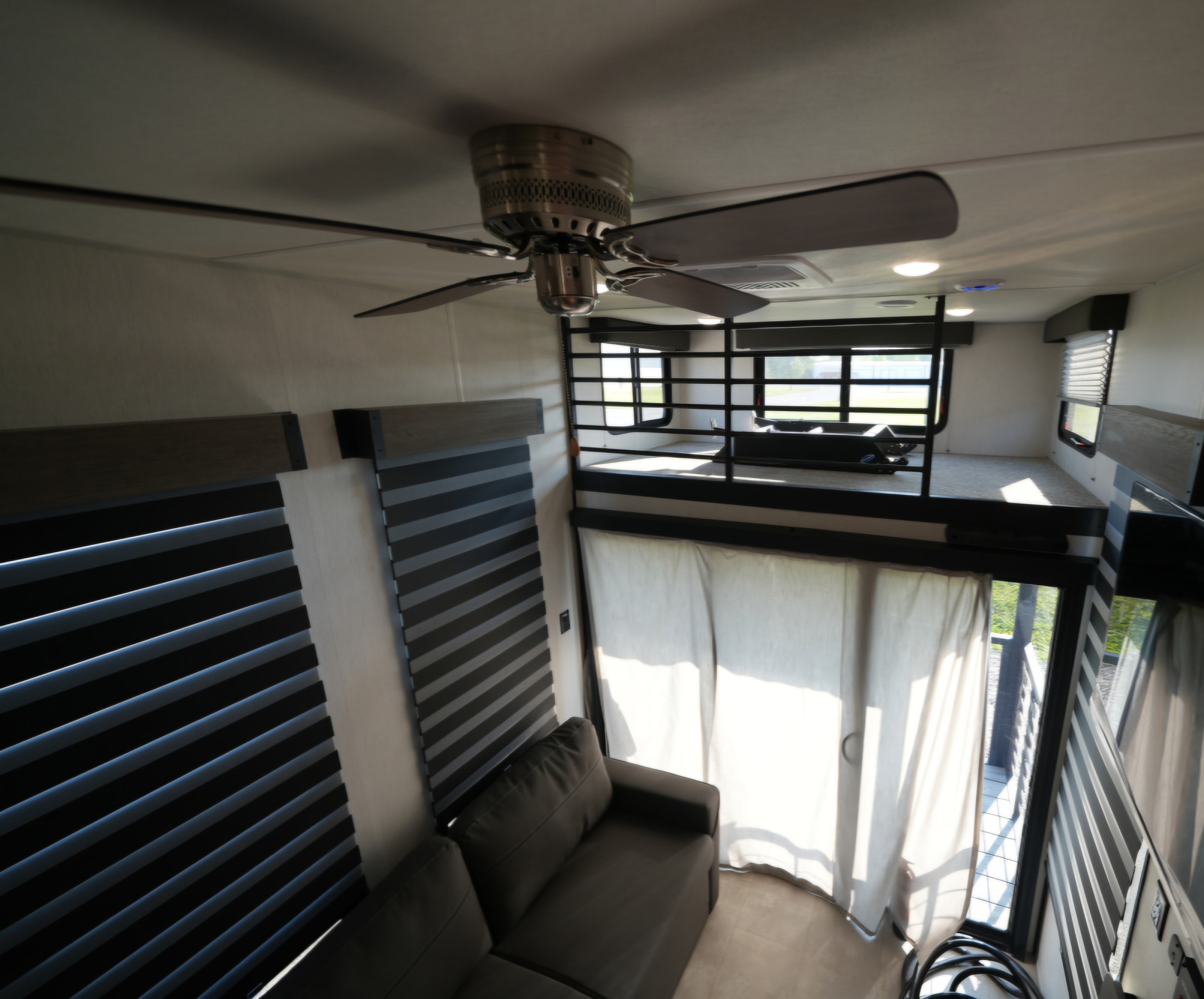 Spacious RV rental interior featuring a modern ceiling fan, comfortable sofa, privacy blinds, and an upper loft area.. Forest River Cherokee Timberwolf 16ML 2024
