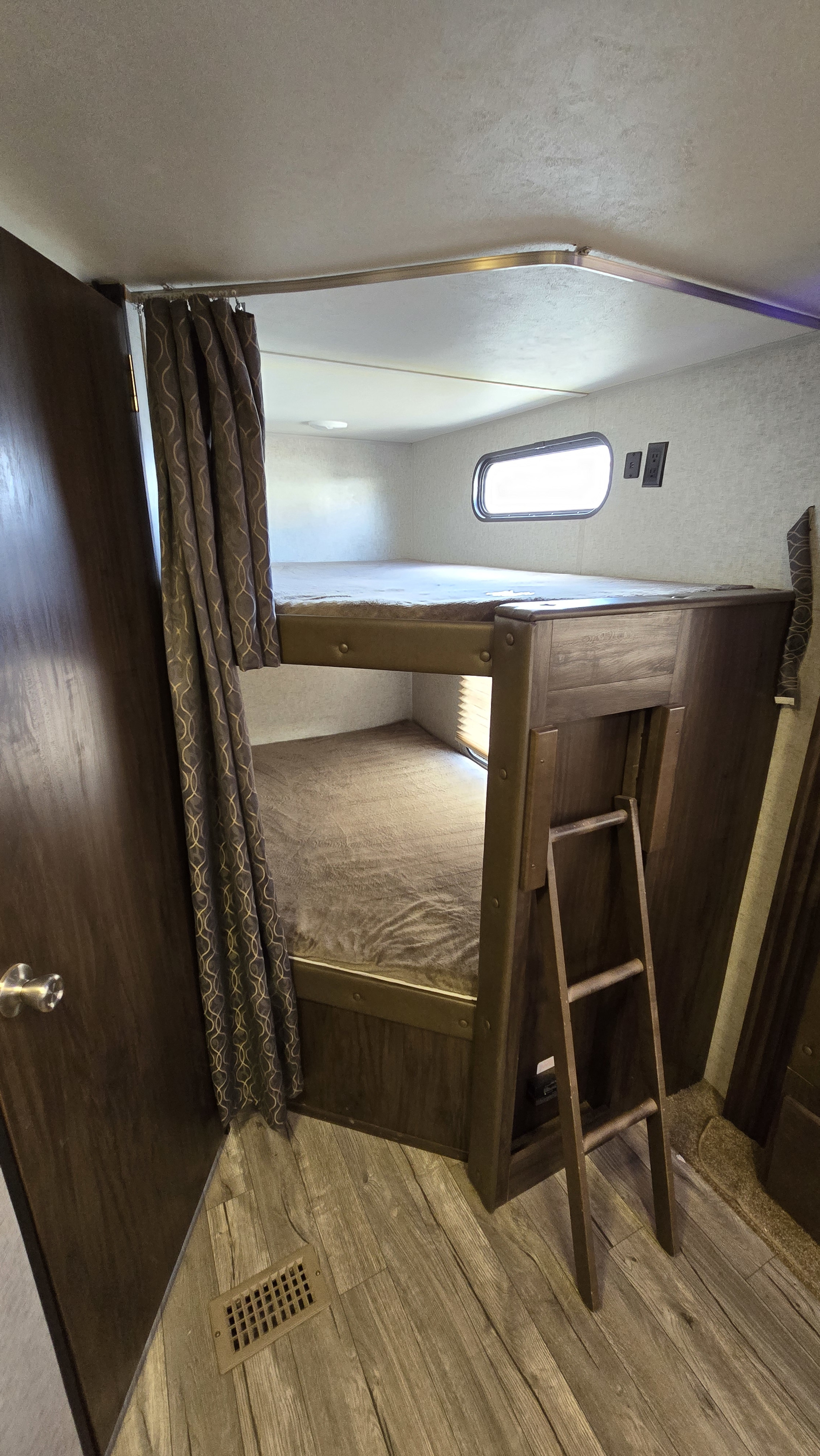 RV rental interior featuring wooden bunk beds with mattresses, a ladder, and a privacy curtain for compact sleeping.. Forest River Cherokee 2019