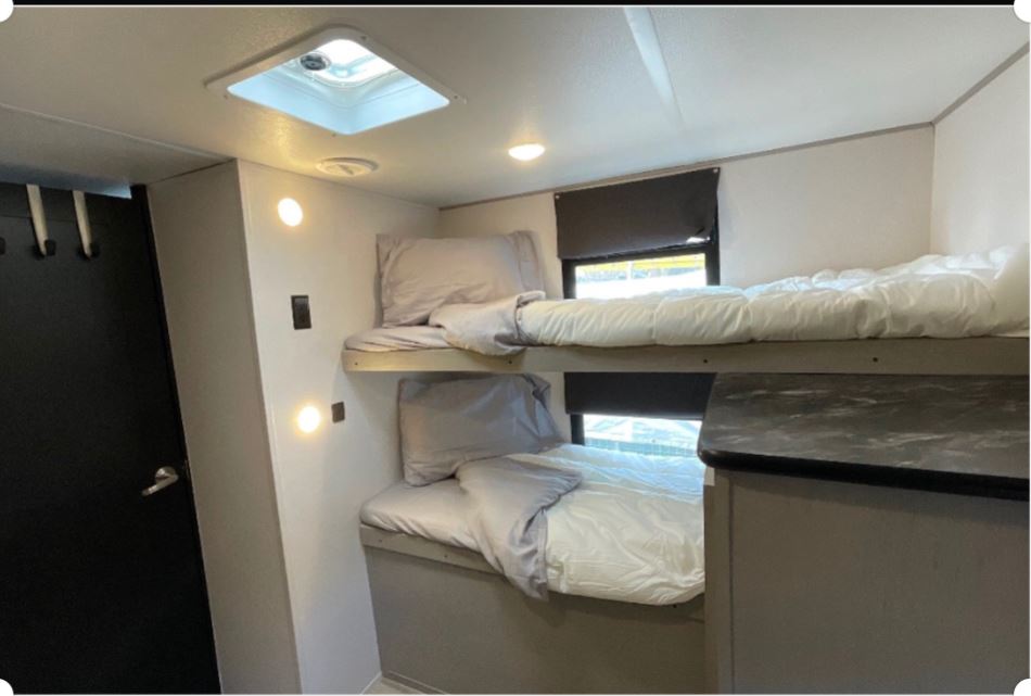 RV rental bunk beds. Cozy sleeping area with two beds and natural light from the skylight and windows.. Forest River Prime Time Tracer 2021
