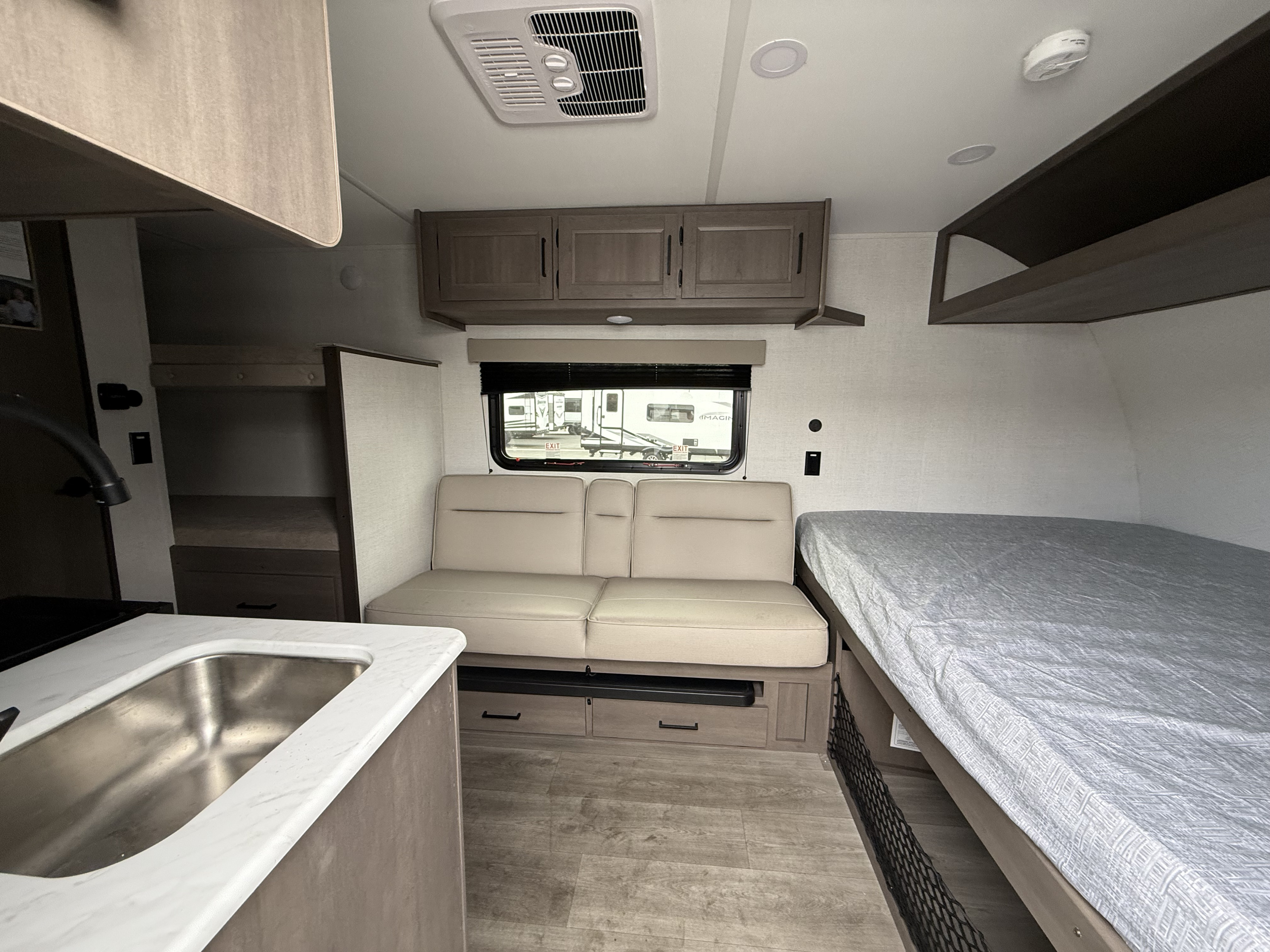 Inside this RV rental: functional kitchen with sink, comfortable dinette, and bed area. Efficient storage for your travels.. Grand Design Transcend One 2025