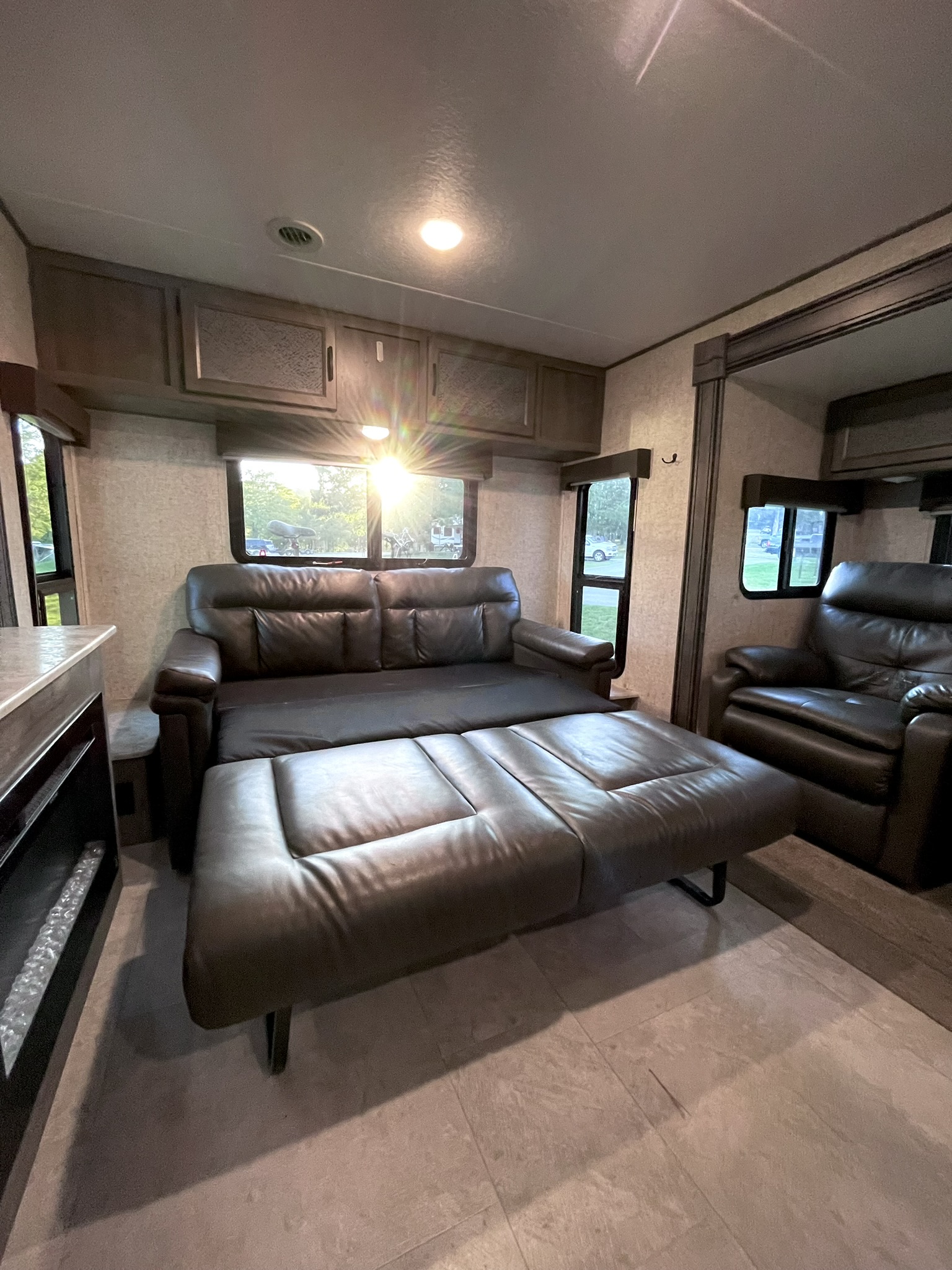 Relax in this comfy RV rental living area with extendable leather sofa, fireplace, and bright windows.. Coachmen Apex 2020