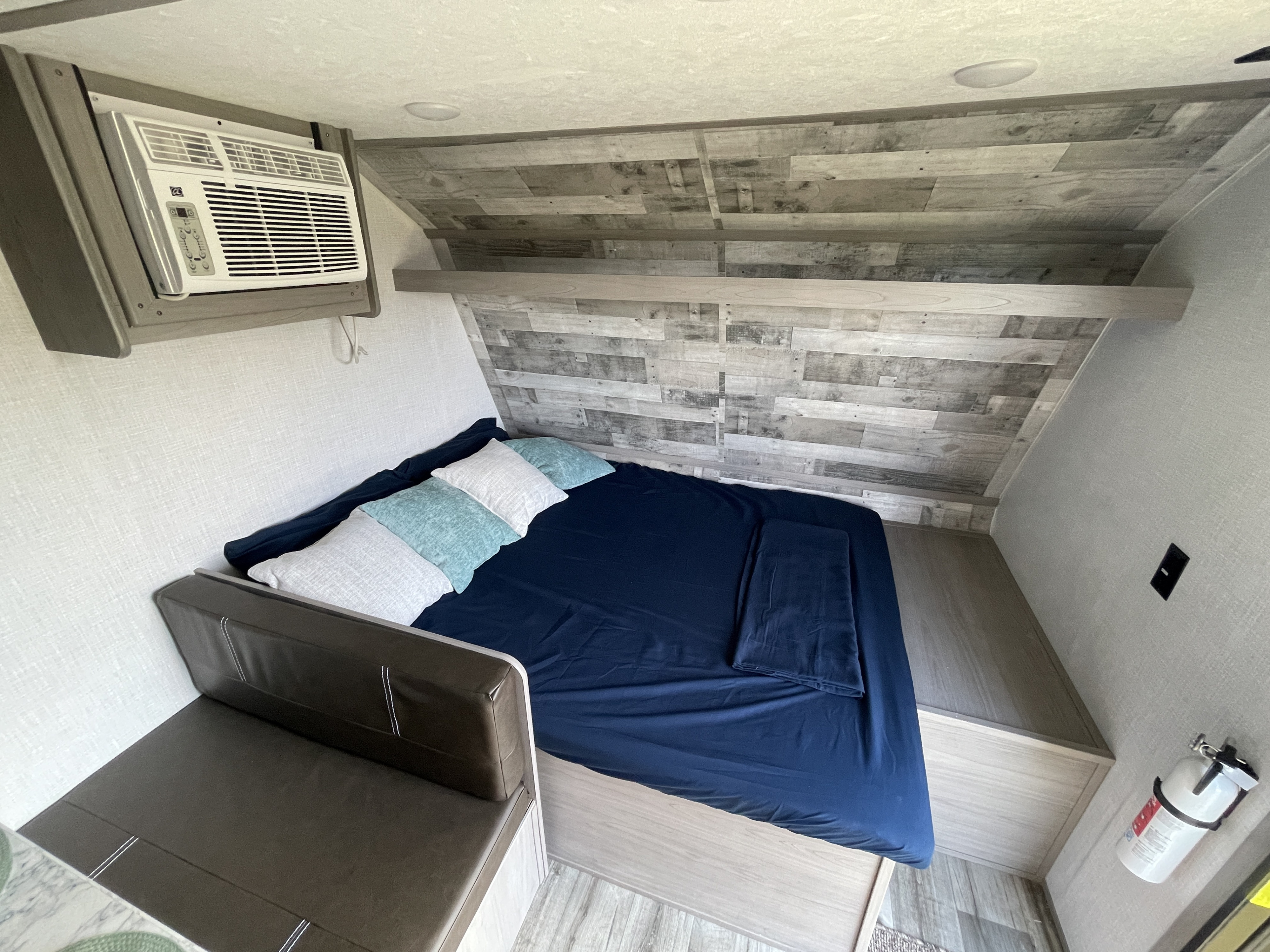 This RV rental features a comfortable sleeping area with a bed, pillows, a cozy couch, and a functional AC unit.. Dutchmen Coleman Lantern LT 2023