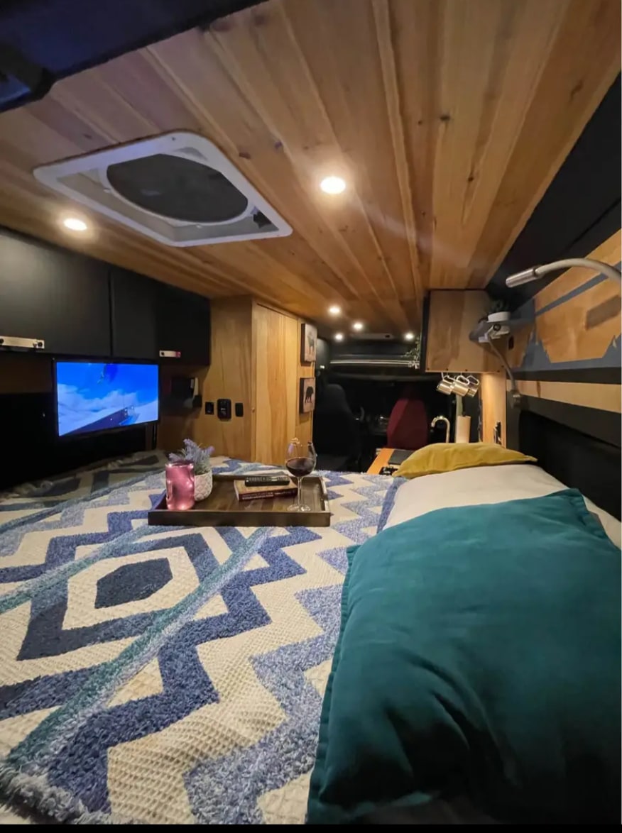 Cozy RV rental interior featuring a comfy bed, TV, and thoughtful amenities, perfect for travel adventures.. Ram Pro Master 2017
