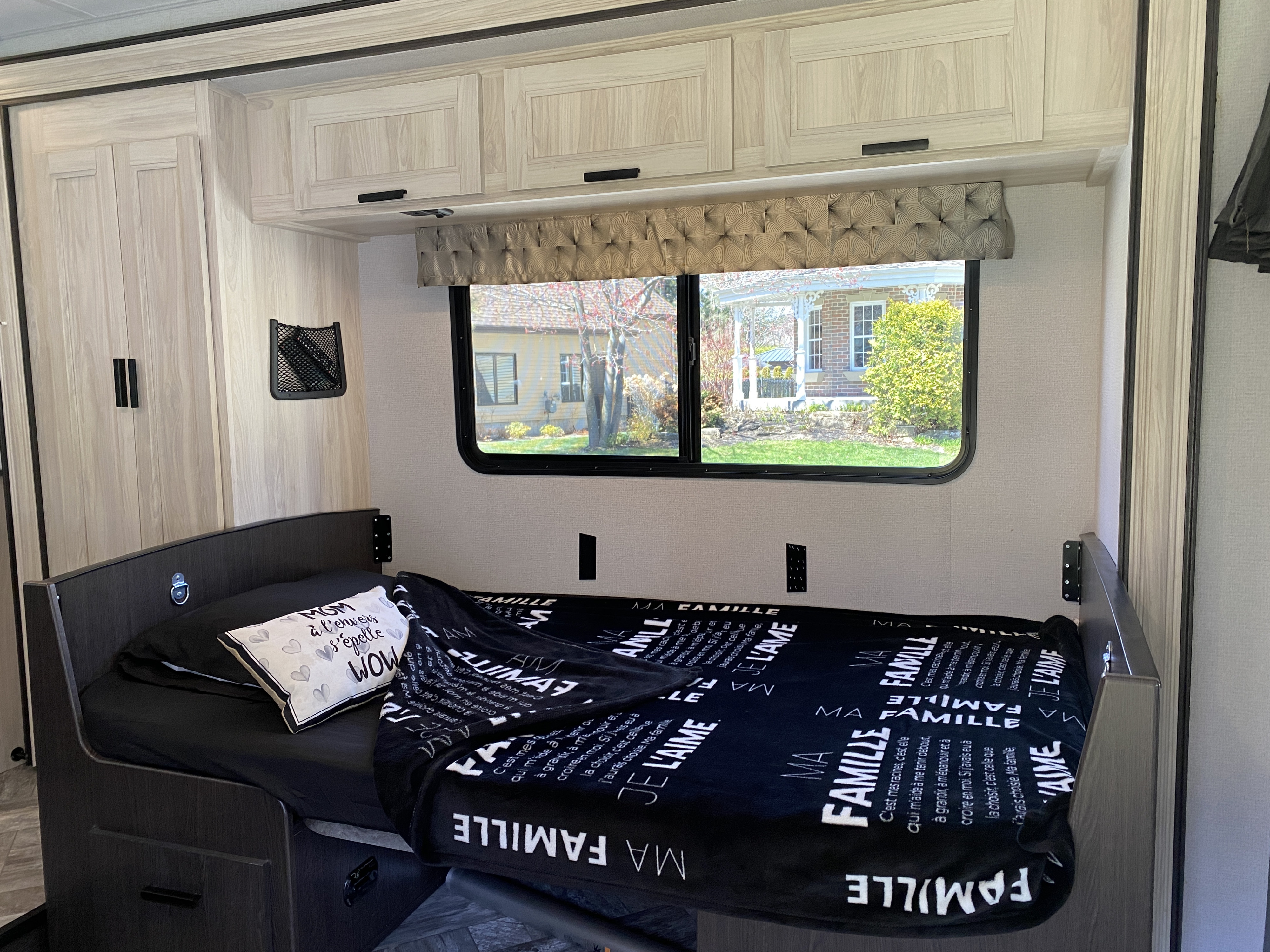 Inside an RV rental: a modern bedroom with a comfortable bed, overhead cabinets, and a window view.. Forest River Sunseeker LE 2021