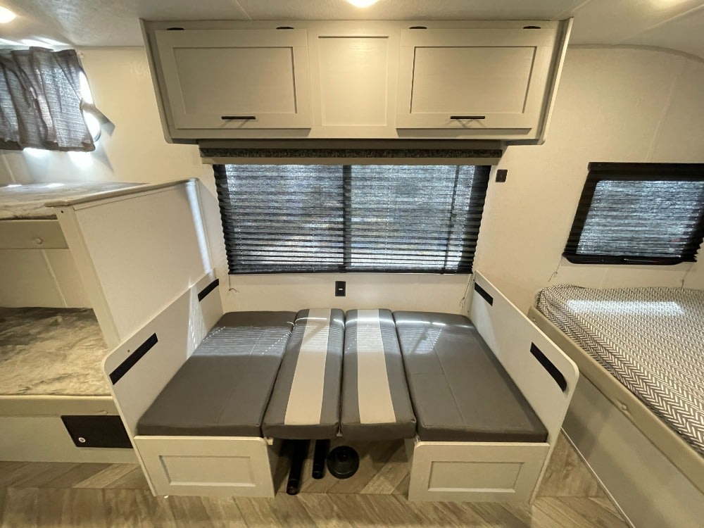 This bright RV rental interior features a convertible dinette, bunk beds, and a cozy bed area, ideal for families.. Forest River Wildwood FSX 2021