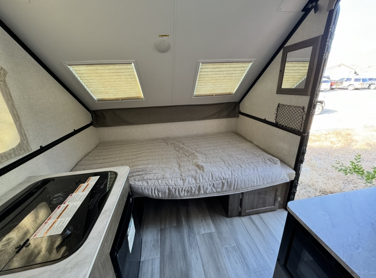 RV rental interior: A cozy bed, two skylights, and a compact kitchen counter with integrated cooktop/sink. Ideal camper setup.. Forest River Rockwood LTD 2023