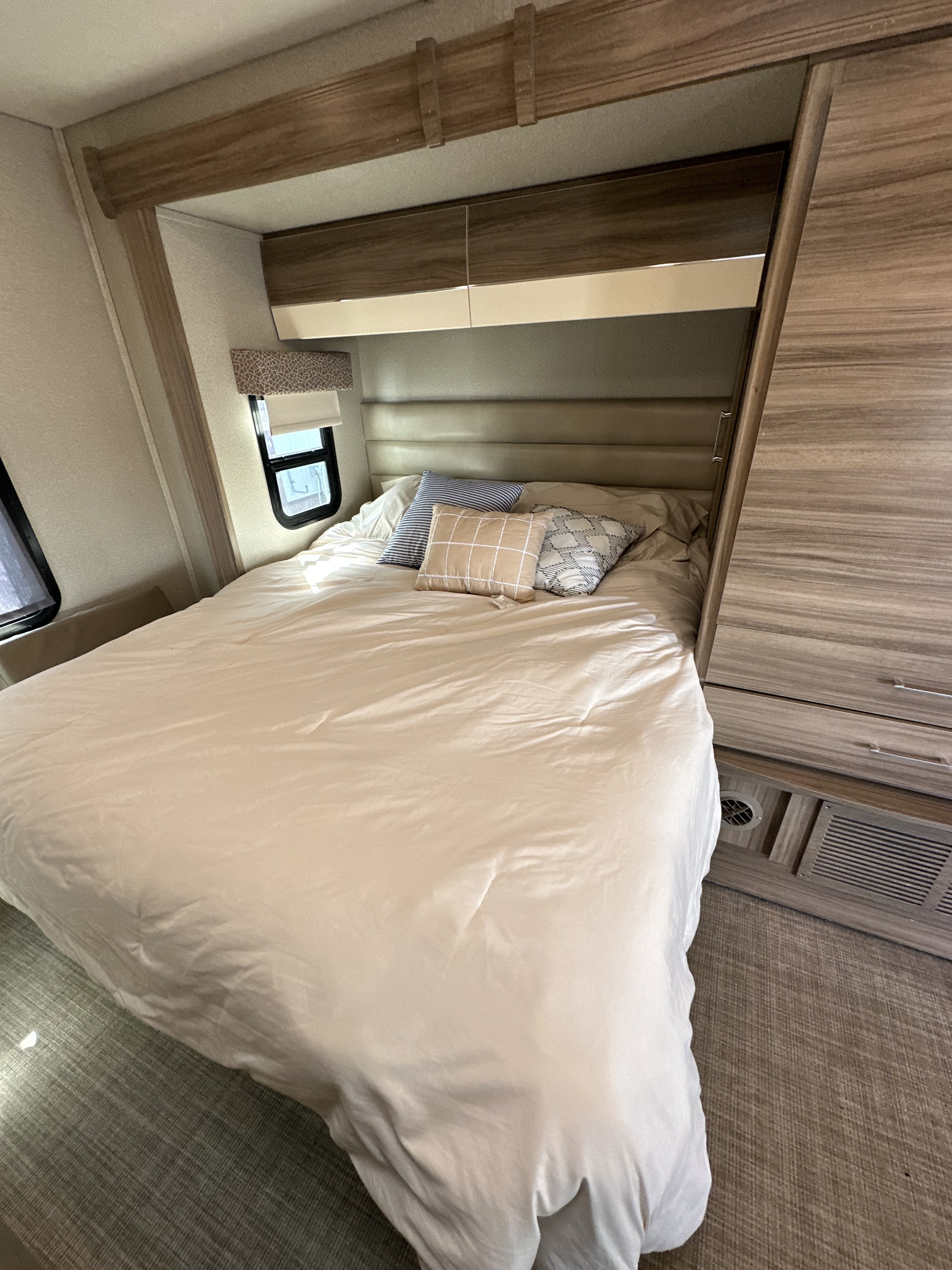 Modern RV rental bedroom with a cozy bed, neutral linens, overhead cabinets, and built-in storage solutions.. Jayco Melbourne 2018