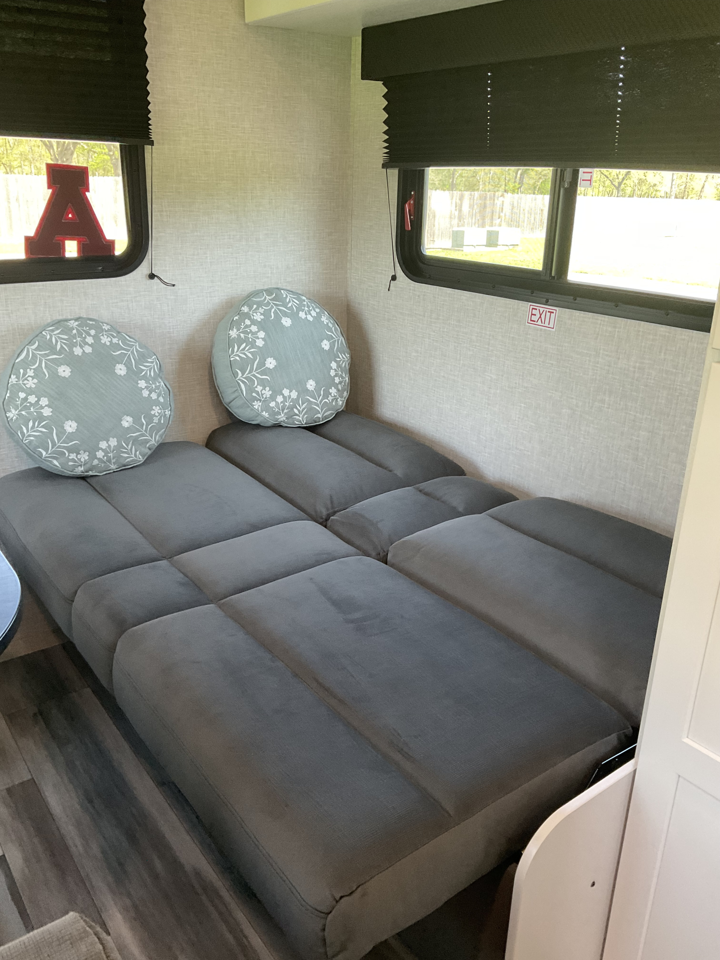 RV rental's inviting interior: gray modular bed, decorative floral pillows, and bright windows.. Jayco Jay Flight SLX 210QB 2025