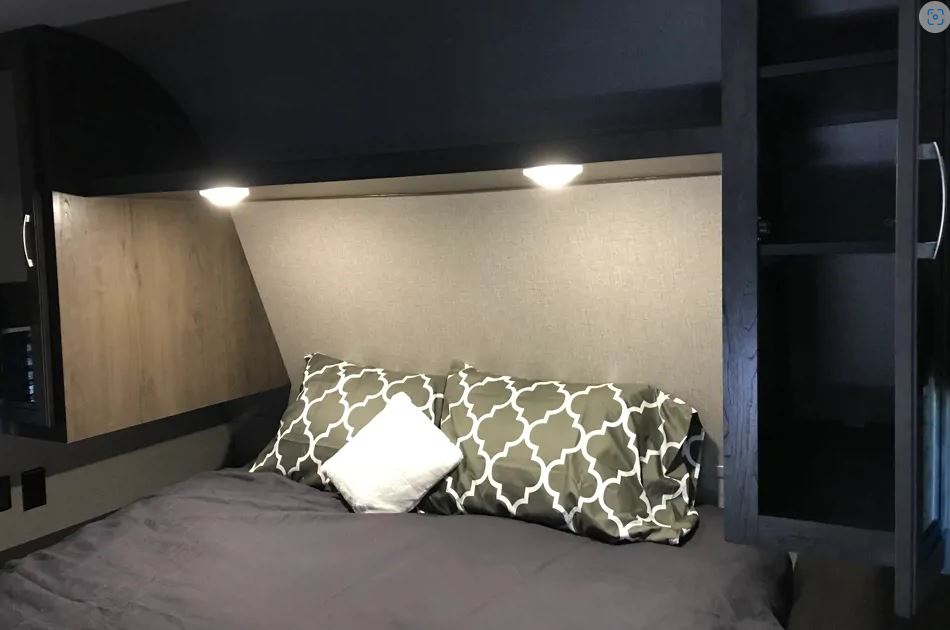 Cozy RV rental bedroom featuring dark bedding, modern reading lights, and built-in storage for a comfortable trip.. Jayco Jay Flight 2020