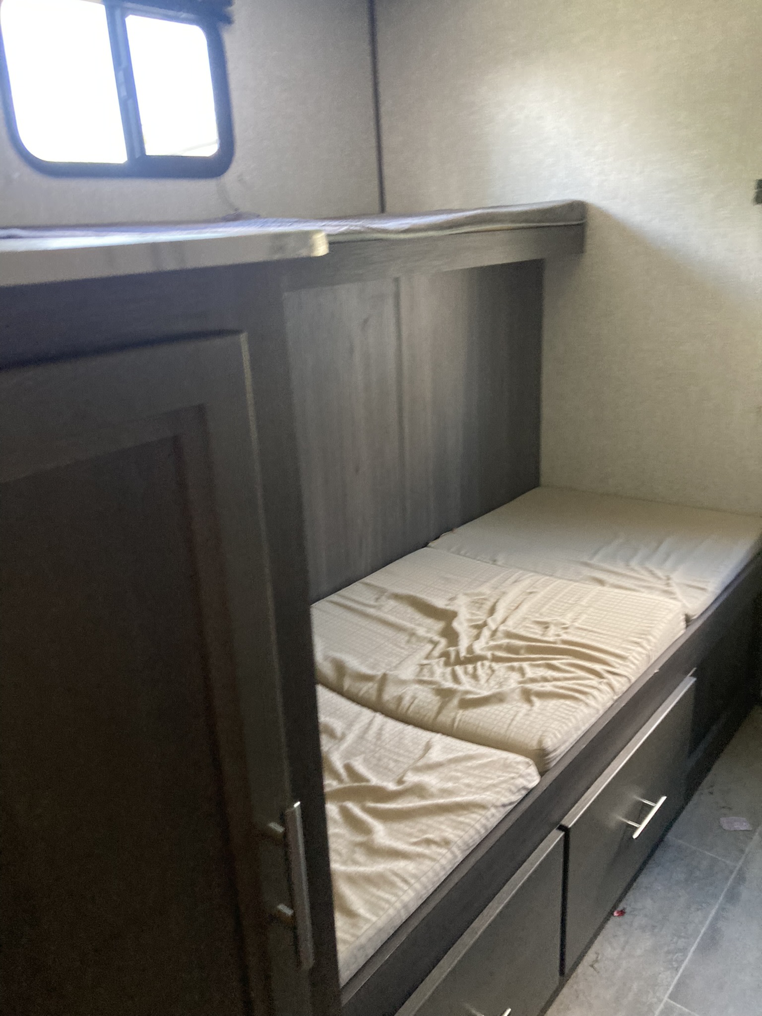 RV rental bunk beds with built-in storage drawers below and a window. Compact sleeping area in this camper interior.. Dutchmen Kodiak Ultimate 2020