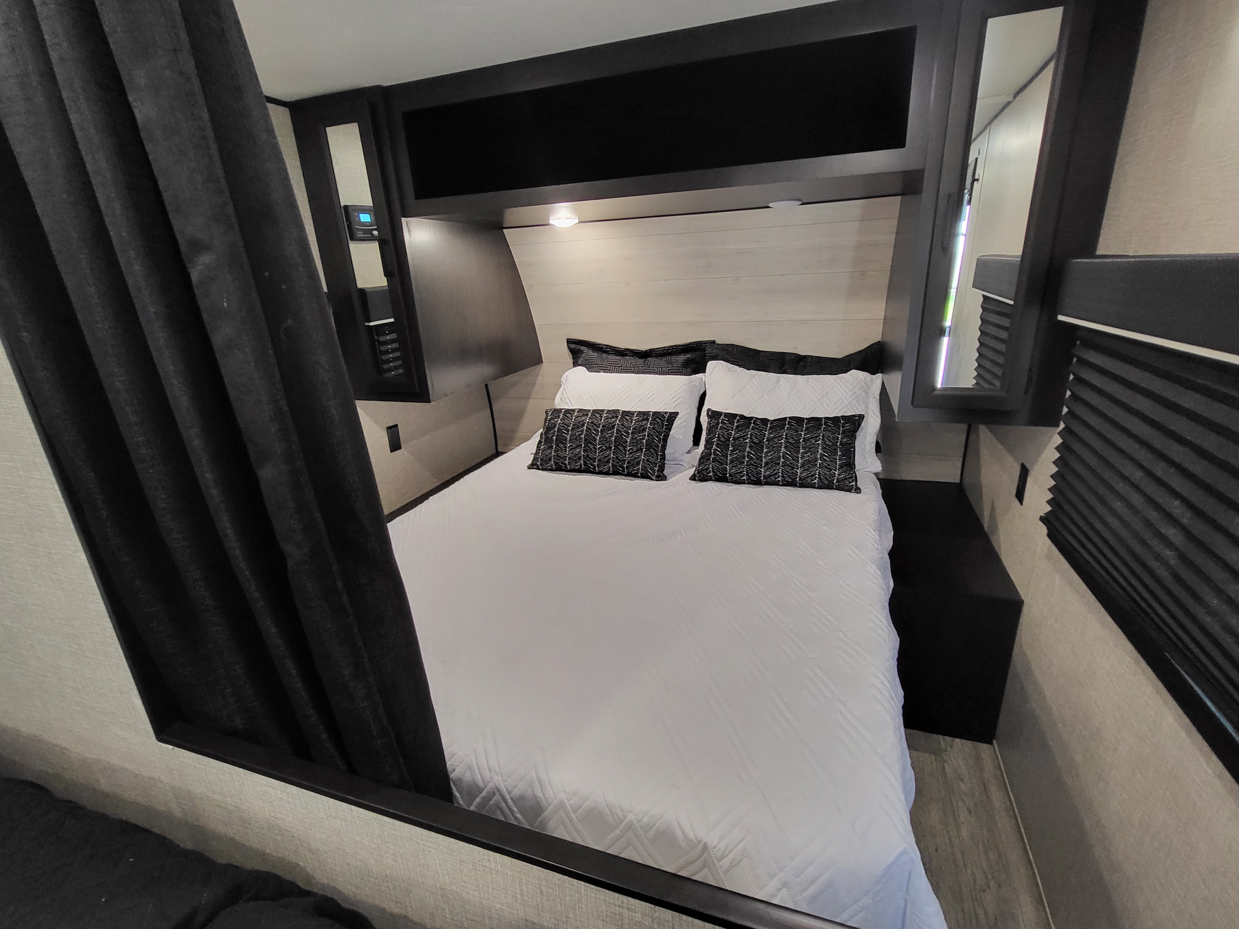 RV rental bedroom with white bed, patterned pillows, shiplap headboard, and overhead storage for travel comfort.. Jayco Jay Flight 2023