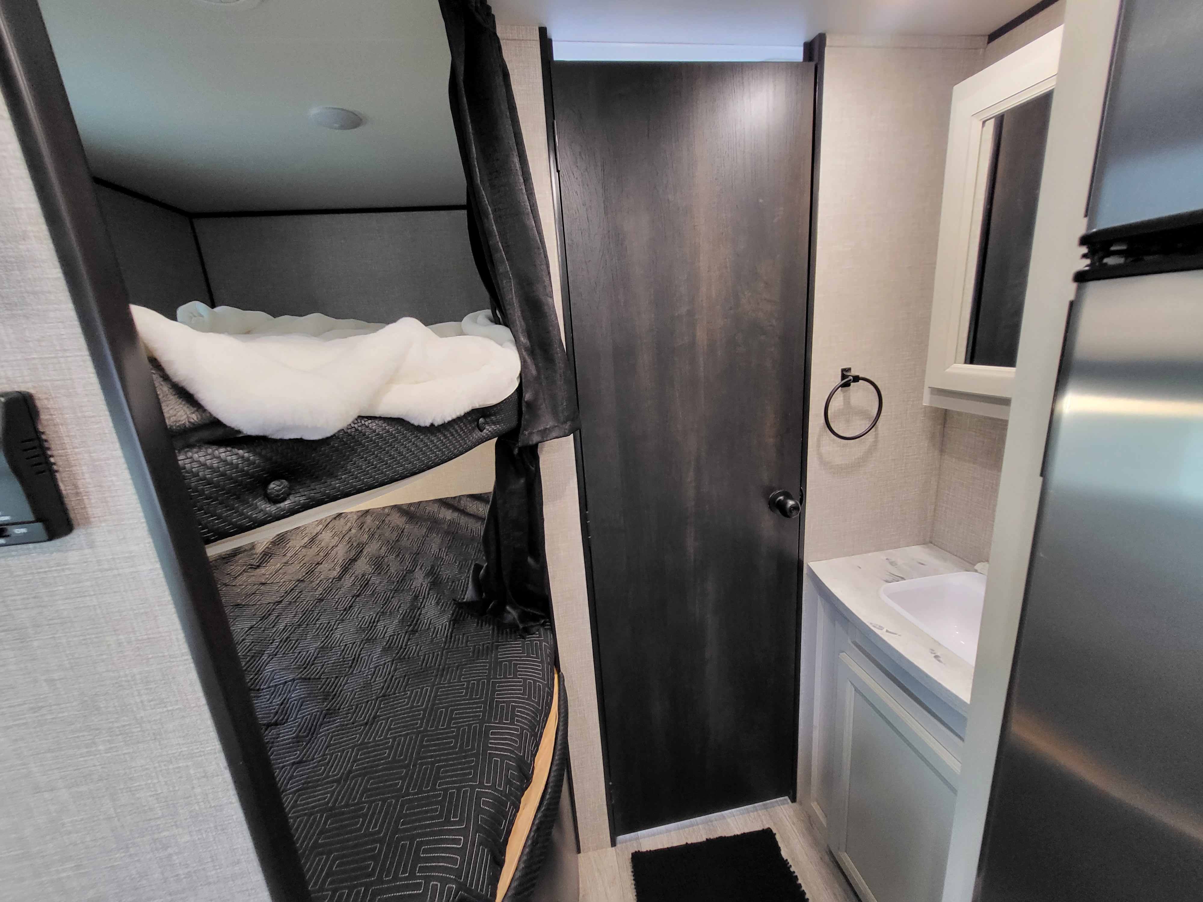 RV rental interior featuring bunk beds, a compact bathroom with sink, and refrigerator. Ideal for family adventures.. Jayco Jay Flight 2023