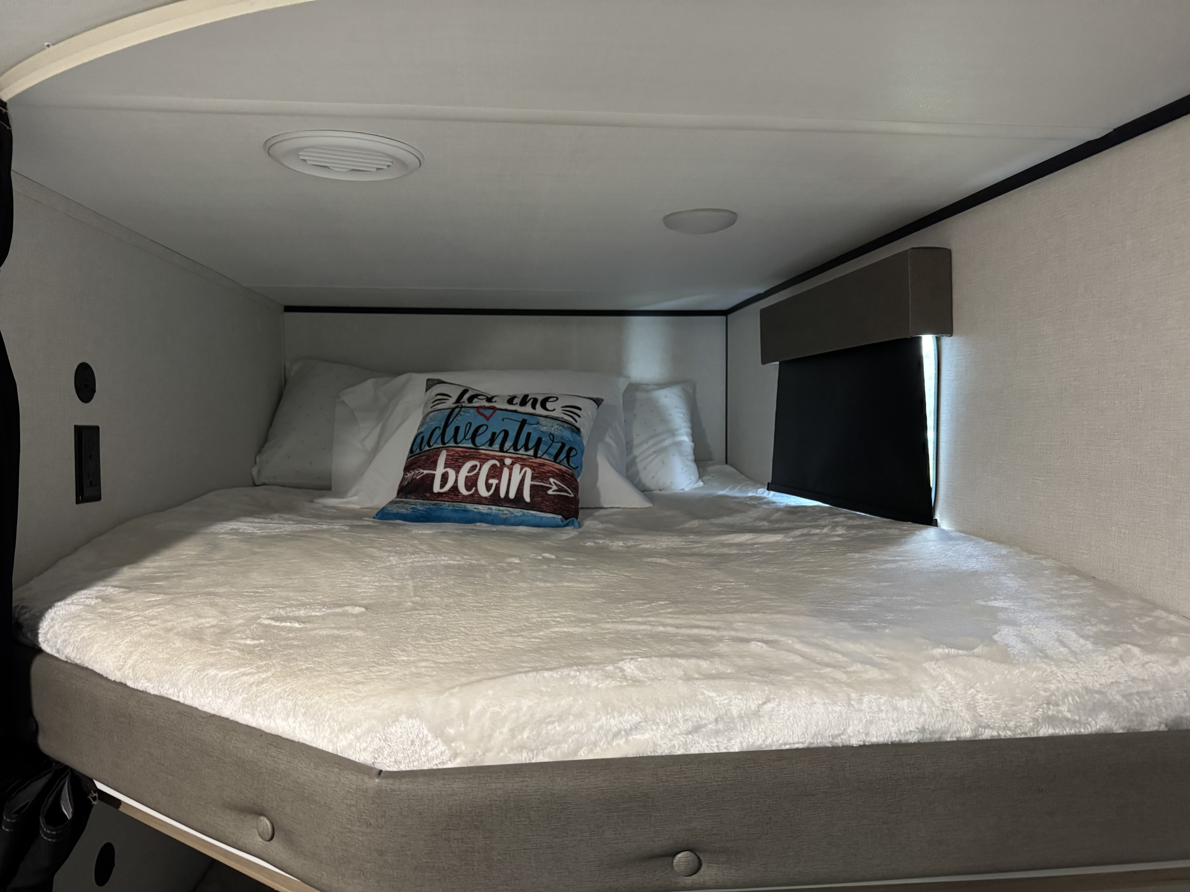 Modern RV rental sleeping space: A fluffy bed, adventure pillow, and convenient outlets in a cozy bunk.. Keystone Coleman Legacy 2900BH 2025