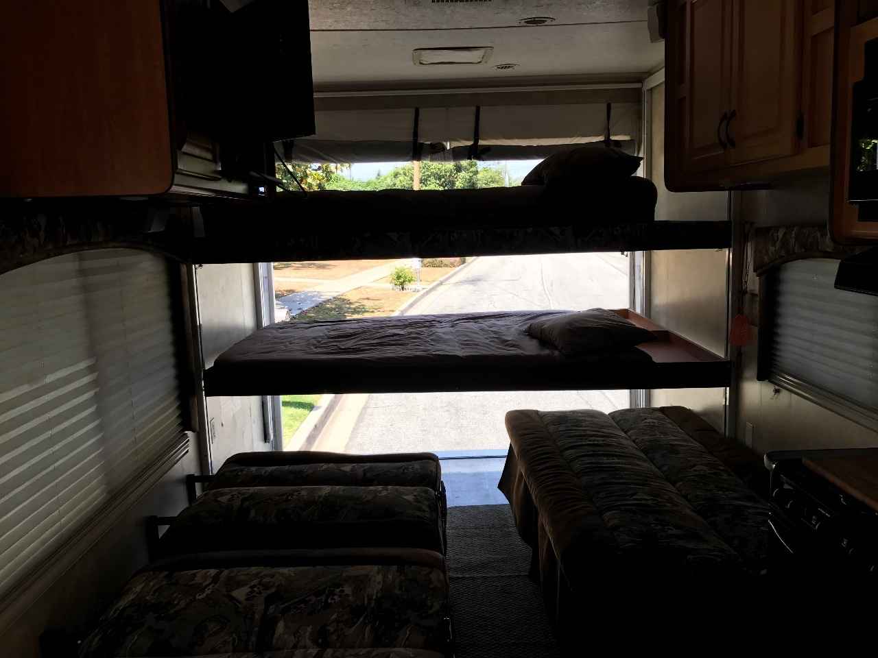 RV rental interior with elevated bunk beds and floor sleeping, rear ramp open to outside. Ideal for group travel.. Thor Motor Coach Vortex 2007