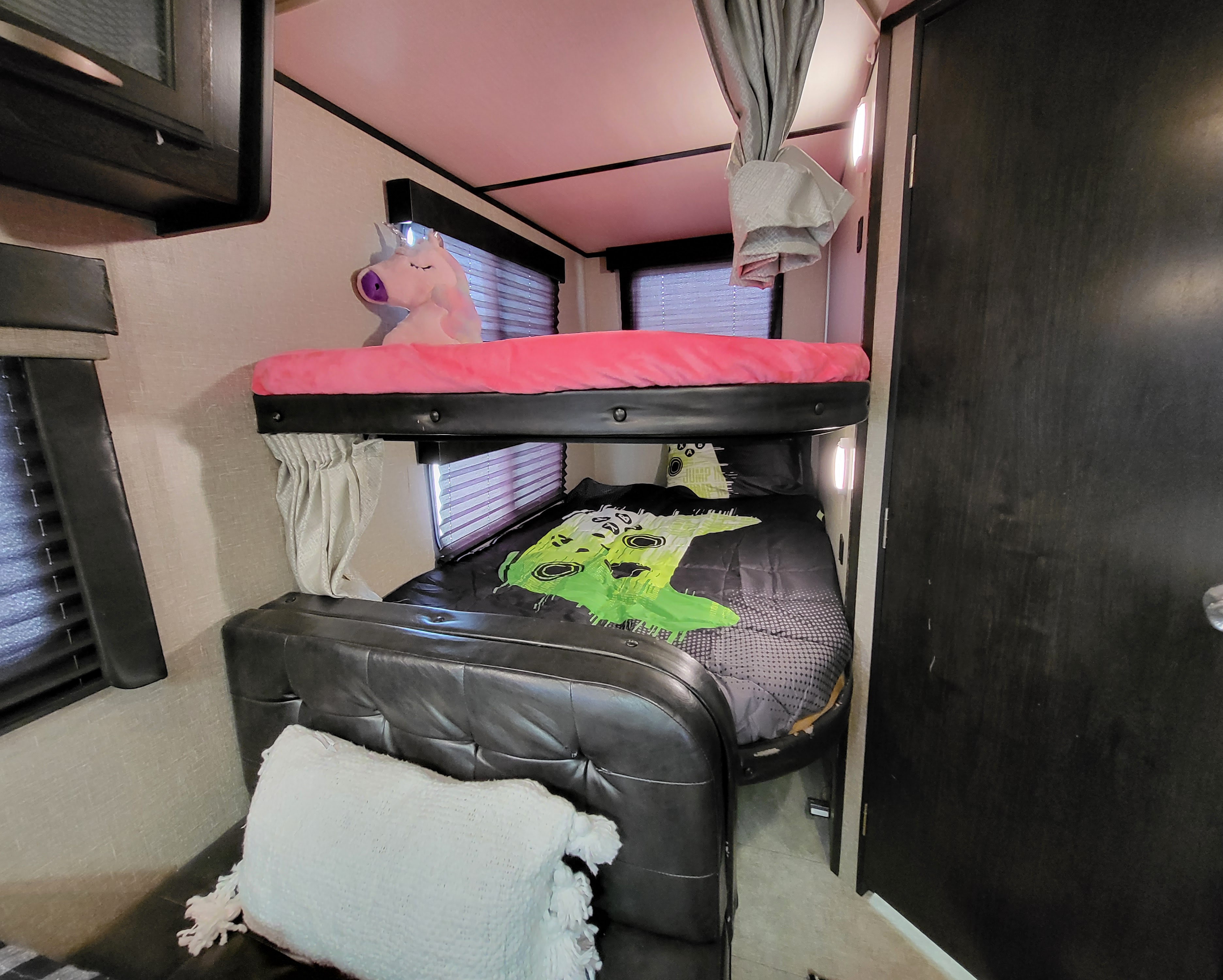 RV rental: Compact sleeping area with bunk beds, playful decor like a unicorn, and window blinds for privacy.. Grand Design Imagine XLS 2019