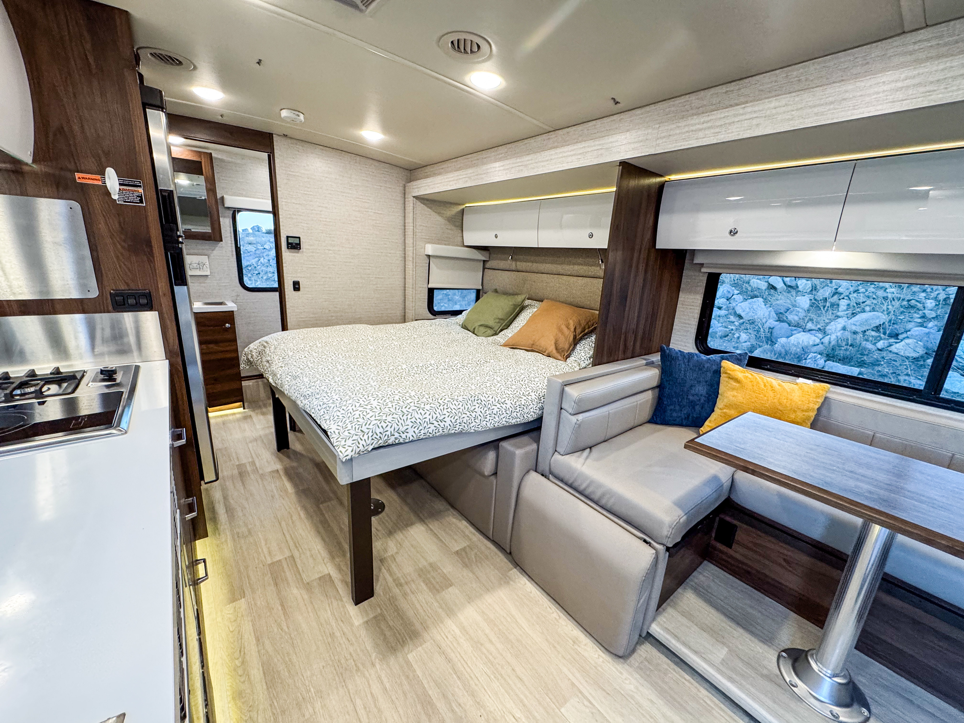 Spacious RV rental interior with a comfortable bed, modern kitchen, and dining lounge, perfect for your next road trip.. Winnebago Navion 2022