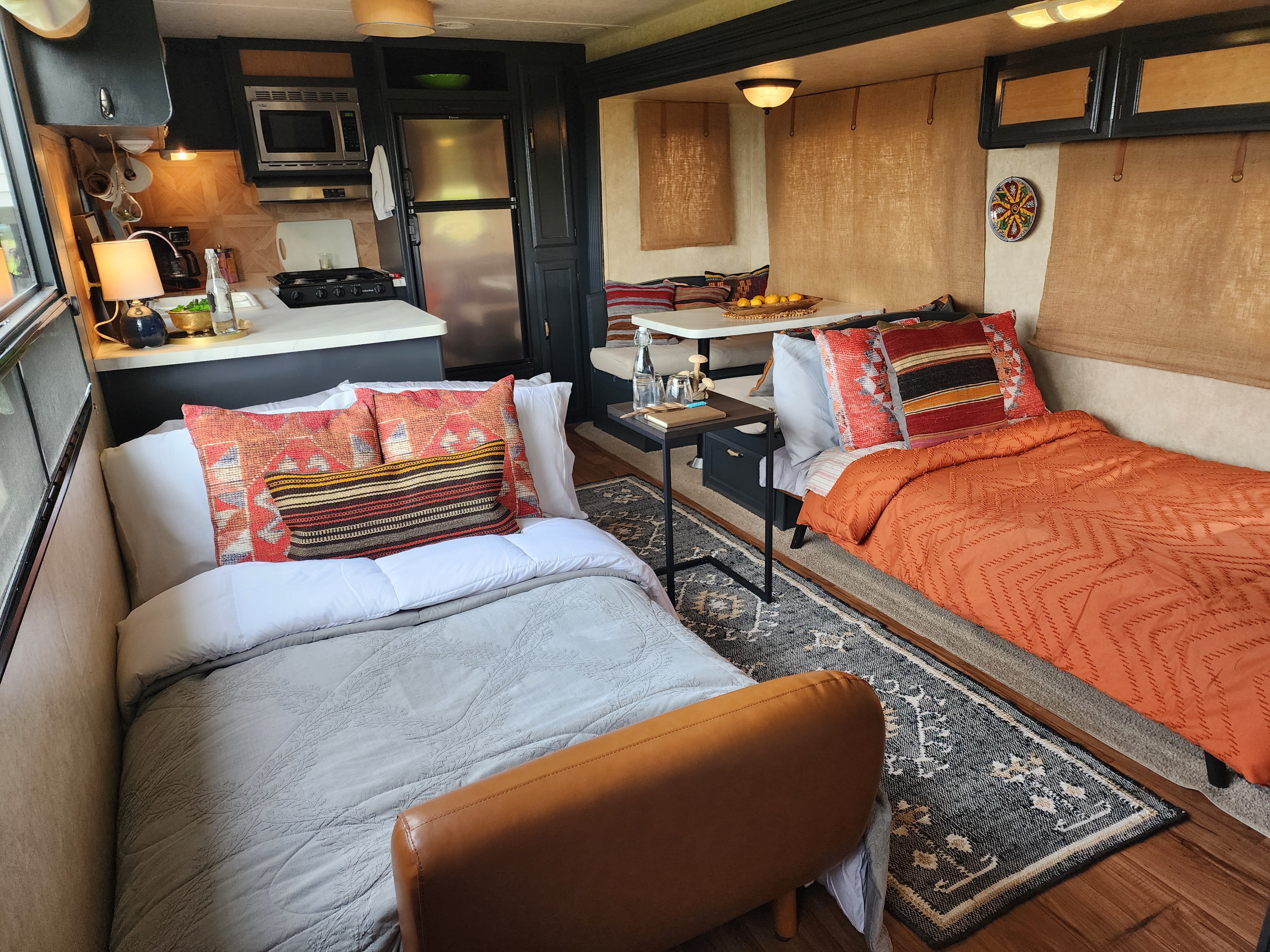 Warm RV rental interior with kitchen, dining, two beds, and inviting decor, offering a cozy travel experience.. Forest River Wildwood 2017