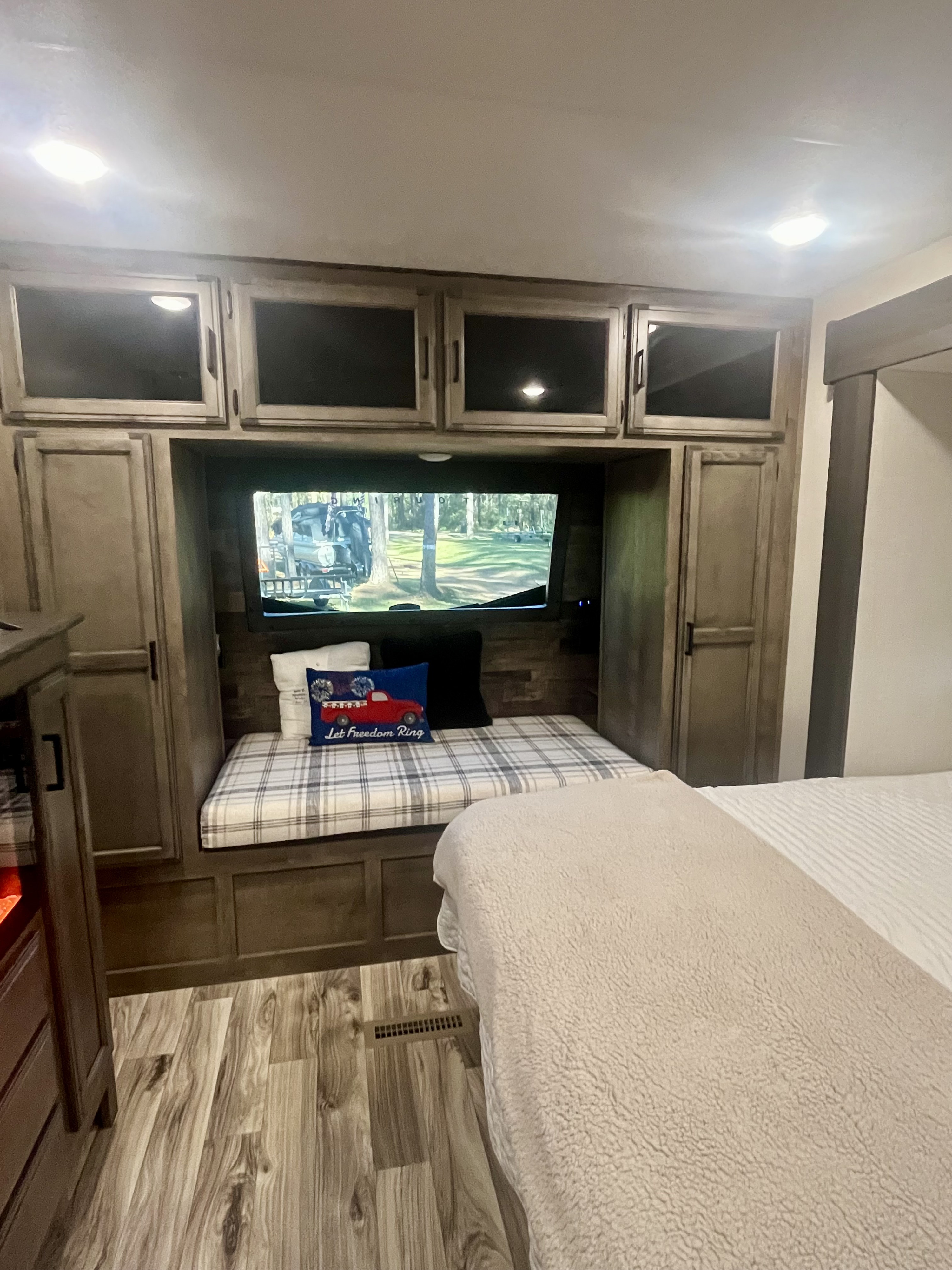 Spacious RV rental bedroom featuring a built-in daybed, TV, cabinetry, and cozy bedding. Ideal for your next trip.. Sport Trek Touring Edition 2024