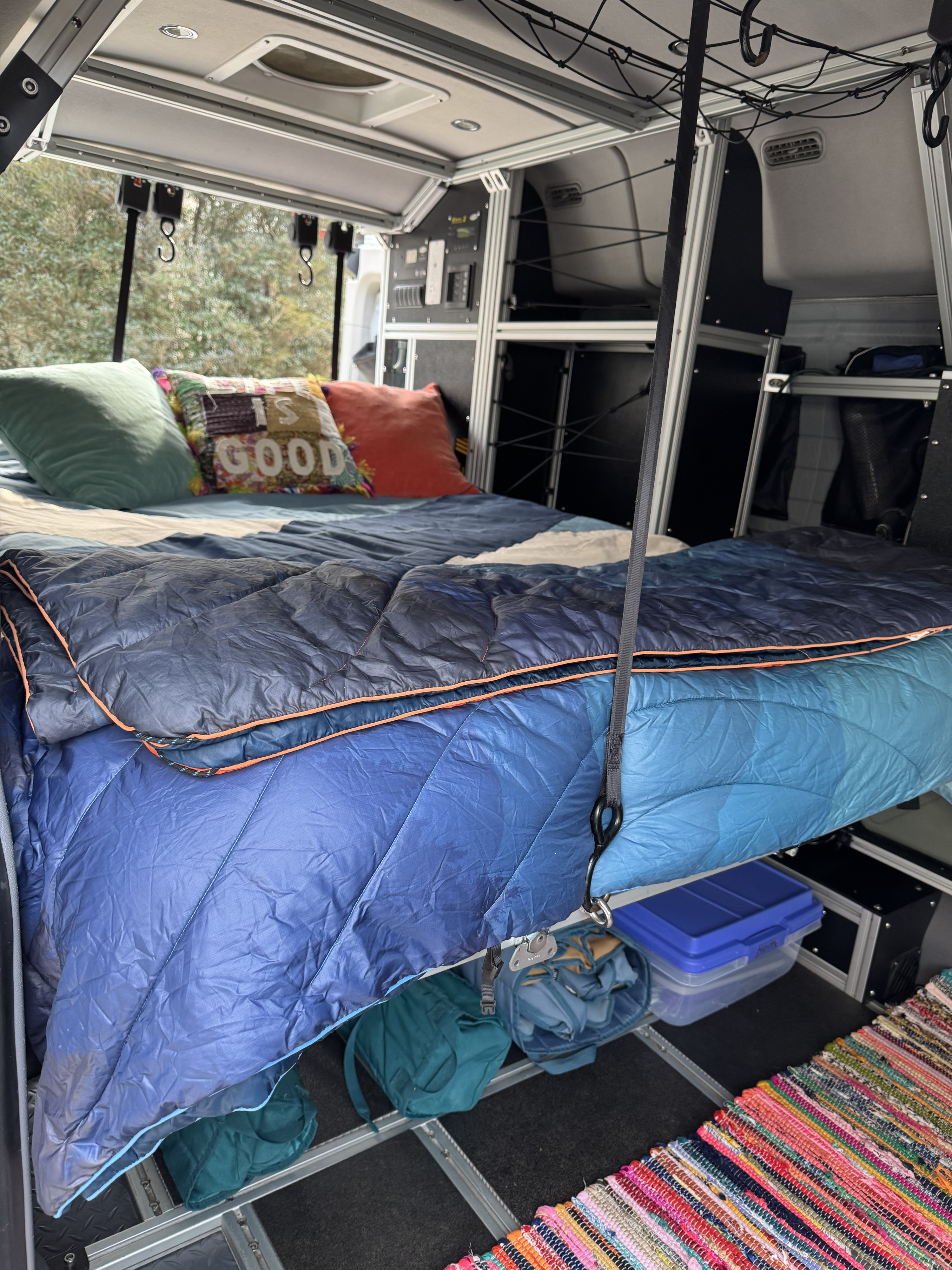 Cozy RV rental interior with a comfy bed, smart storage, and a colorful rug, perfect for mobile adventures.. Ford Transit 2017
