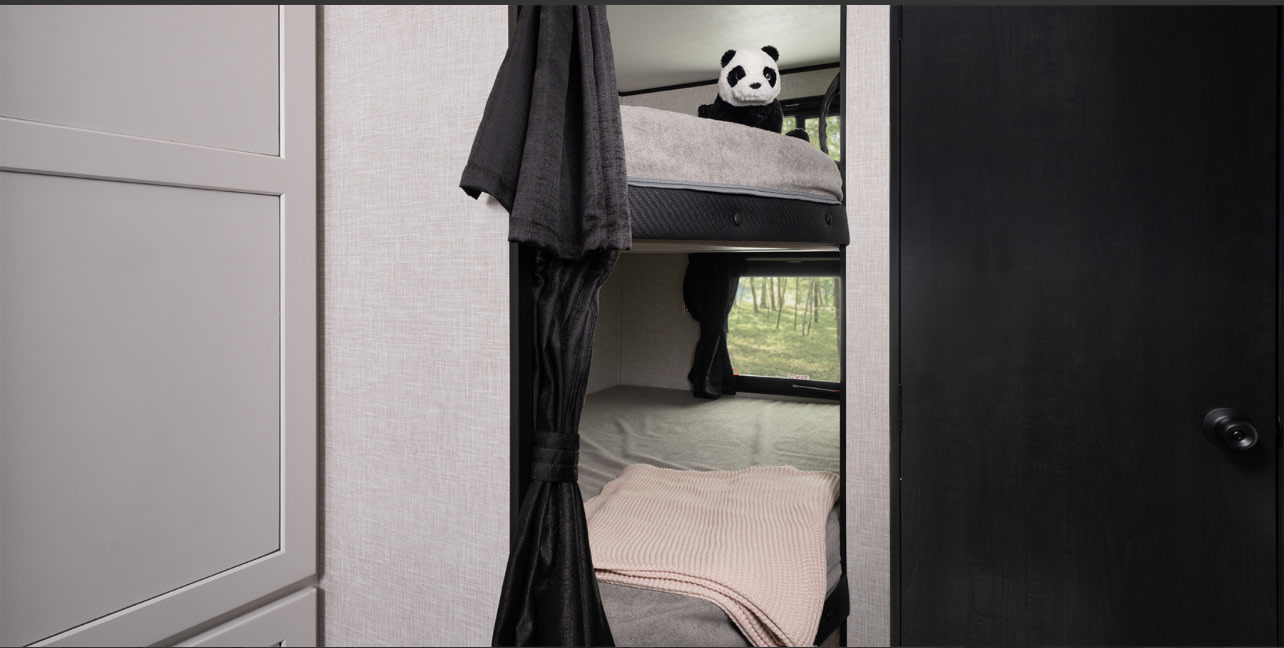 RV rental interior with bunk beds, a playful panda, privacy curtains, and a window to nature.. Jayco Jay Flight 261BHS 2025