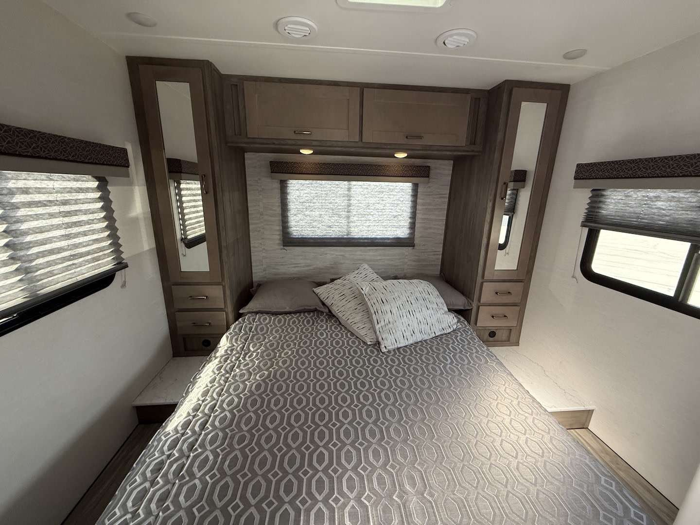 Bright RV rental bedroom featuring a patterned bed, built-in storage, and windows with blinds.. Gulf Stream Conquest (Ford) 6280LE 2025
