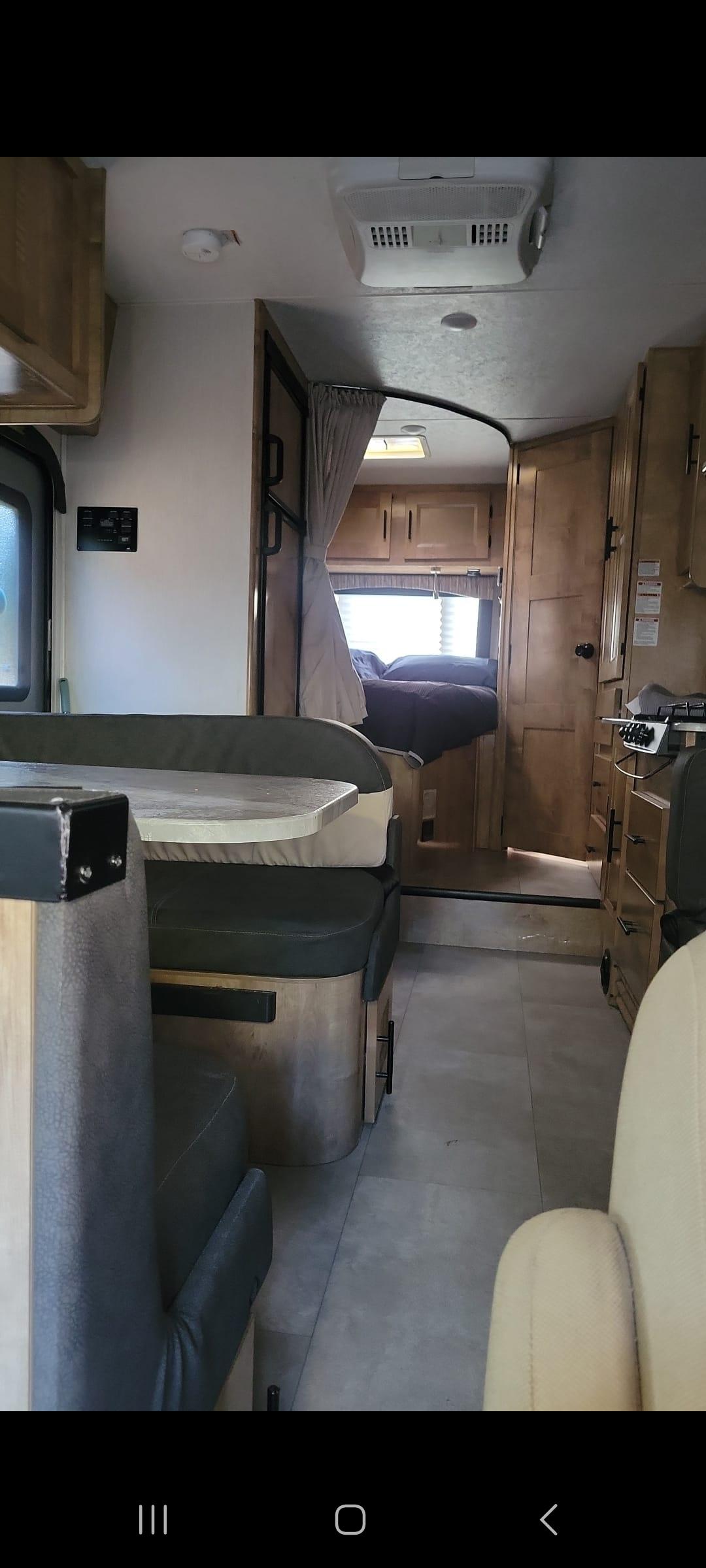Step inside this RV rental, showcasing its dinette, kitchen, and cozy bedroom. A comfortable mobile living space.. Ford coachman leprechaun 2021