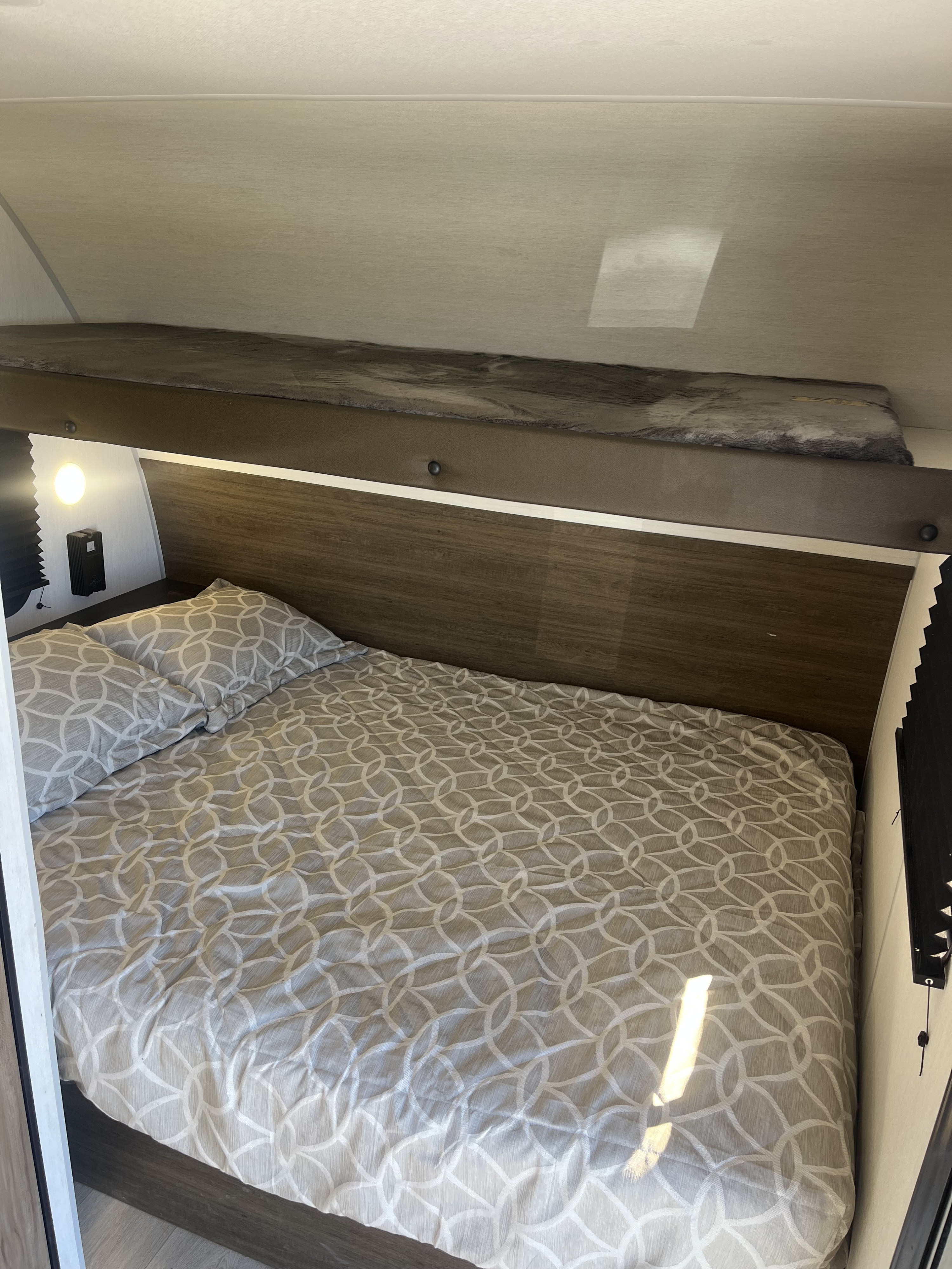 Cozy RV rental bedroom featuring a patterned bed below a top bunk, ideal for families or groups.. Forest River Cherokee Wolf Pup 2025