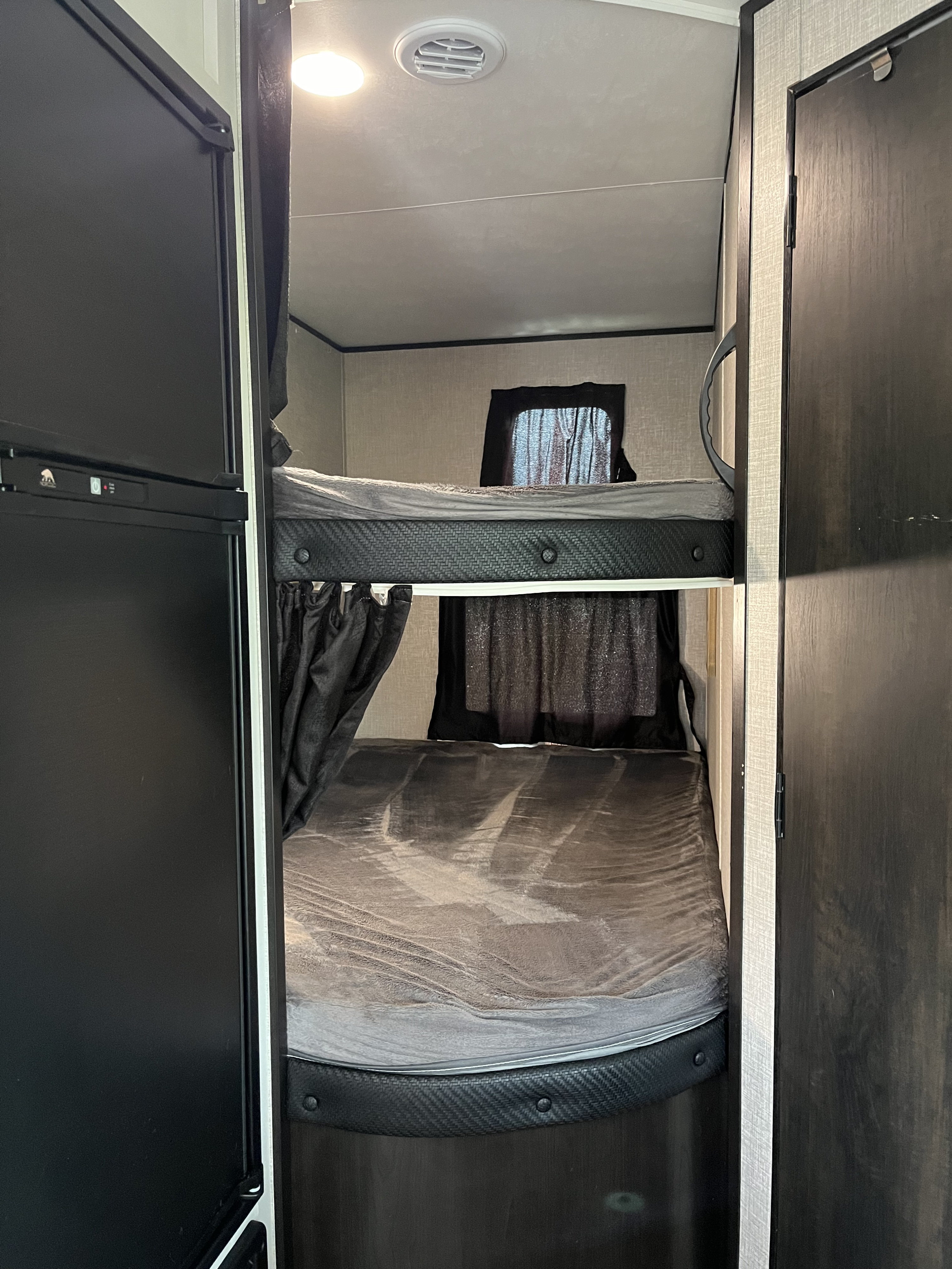 RV rental interior: cozy bunk beds with curtains & a refrigerator. Compact sleeping for travel adventures.. Jayco Jay Flight 2022
