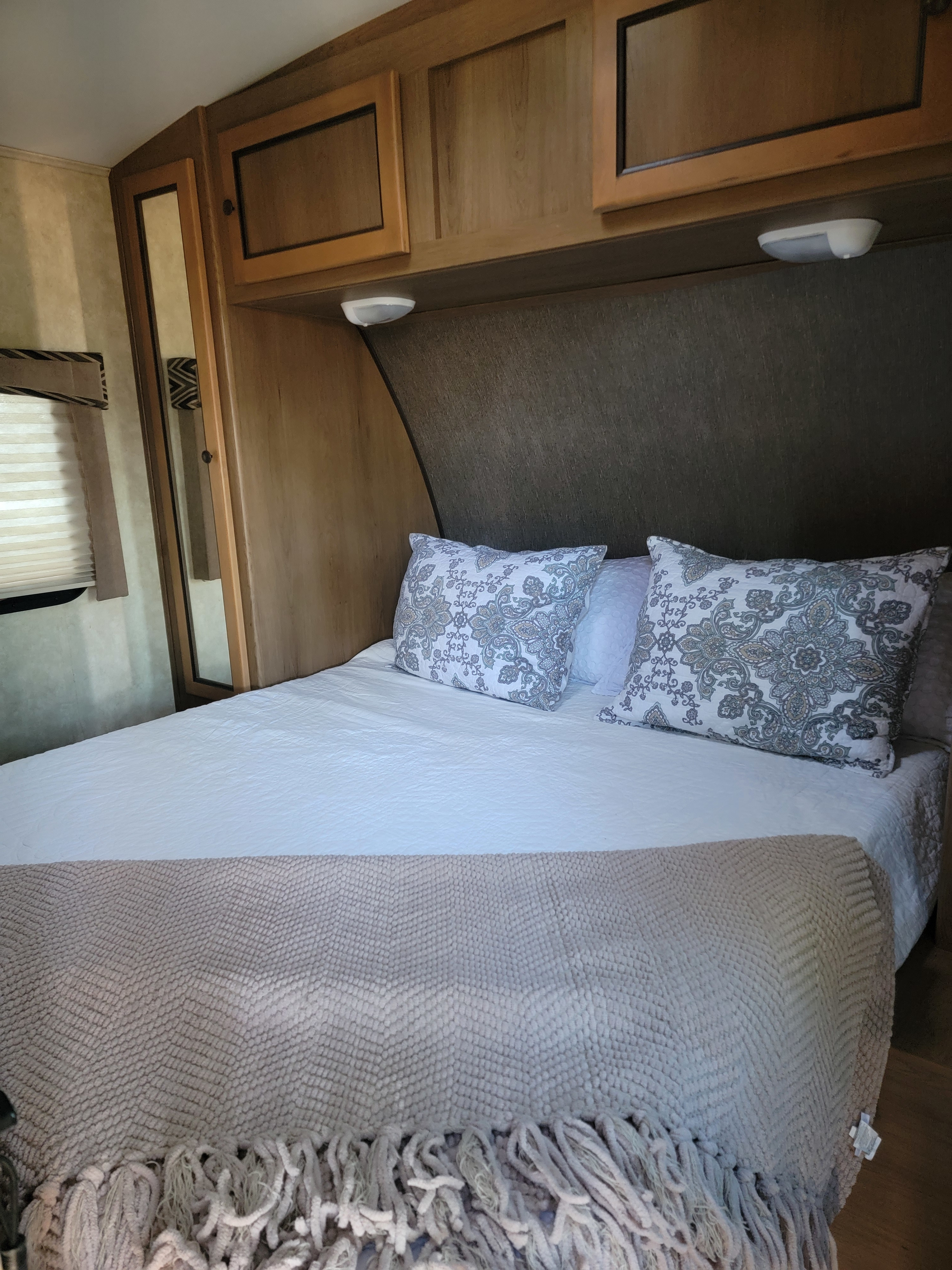 Cozy RV rental bedroom with patterned pillows, clean bedding, and practical overhead storage cabinets.. 5RXTD2221F1032421 Shadow Cruiser 2015